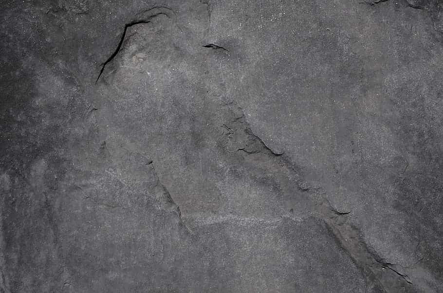 Grey Texture 桌布 壁紙 — 粗糙深灰色岩石表面的特寫，帶有自然裂縫和微妙的紋理變化。