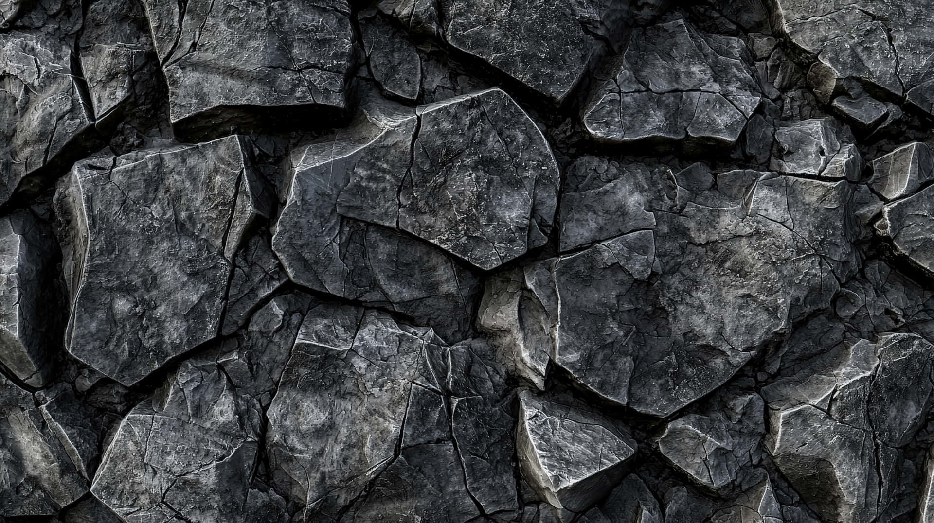 Dark Cracked Stone Wall Texture 壁紙 — 粗糙深灰色火山岩碎片的特寫，具有鋒利的邊緣和深裂縫。