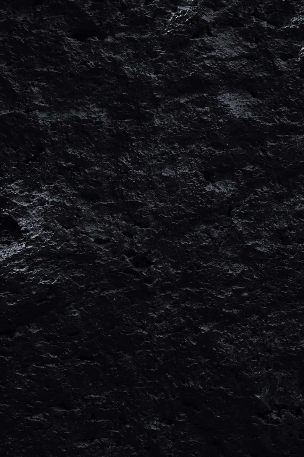 Dark Phone 桌布 壁紙 — 粗糙深色紋理表面的特寫，帶有微妙的灰色亮點和深色陰影。