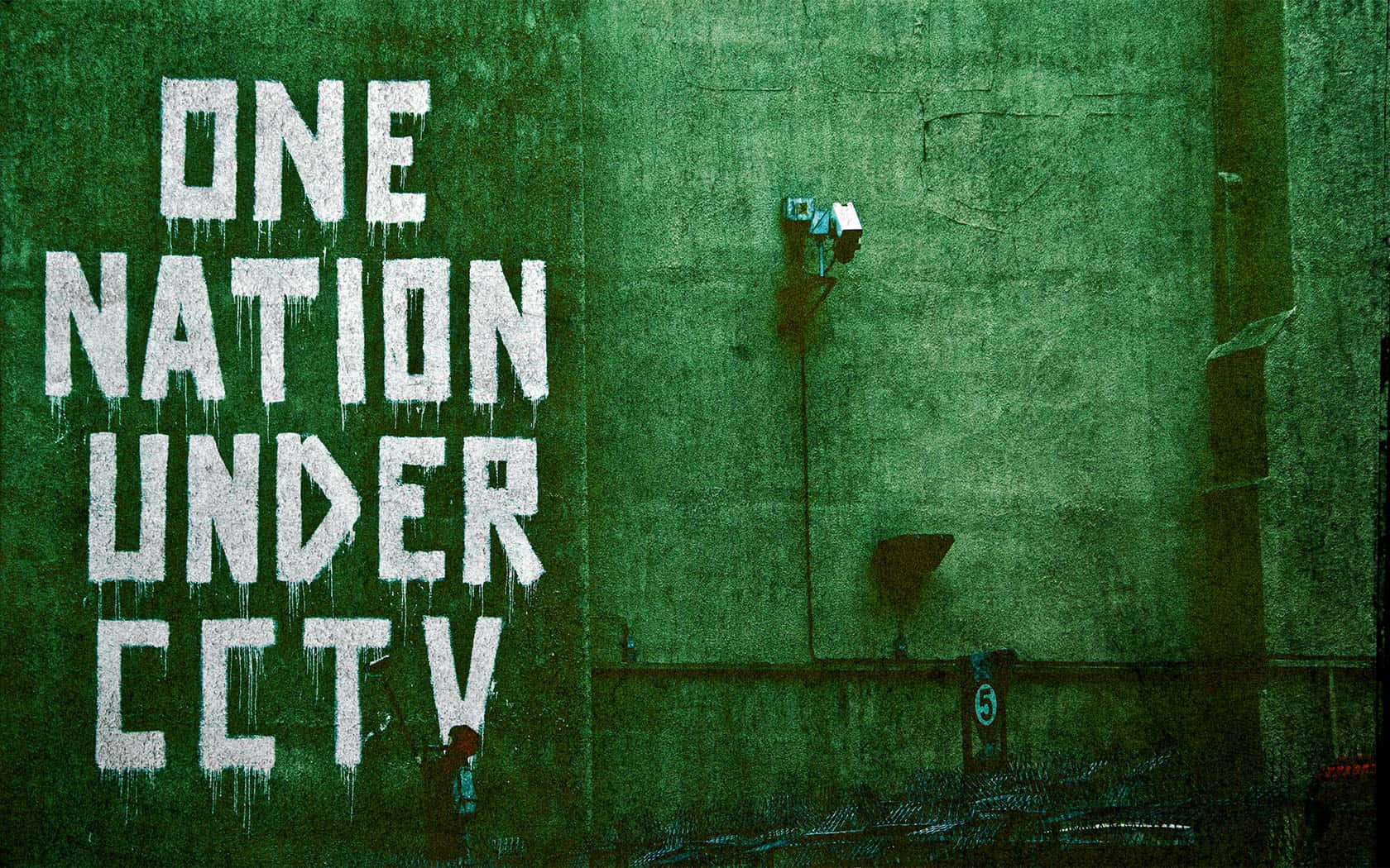 Banksy 桌布 壁紙 — 粗糙的綠色混凝土牆上帶有粗體白色塗鴉，寫著「ONE NATION UNDER CCTV」，附近安裝了一個安全攝像頭。
