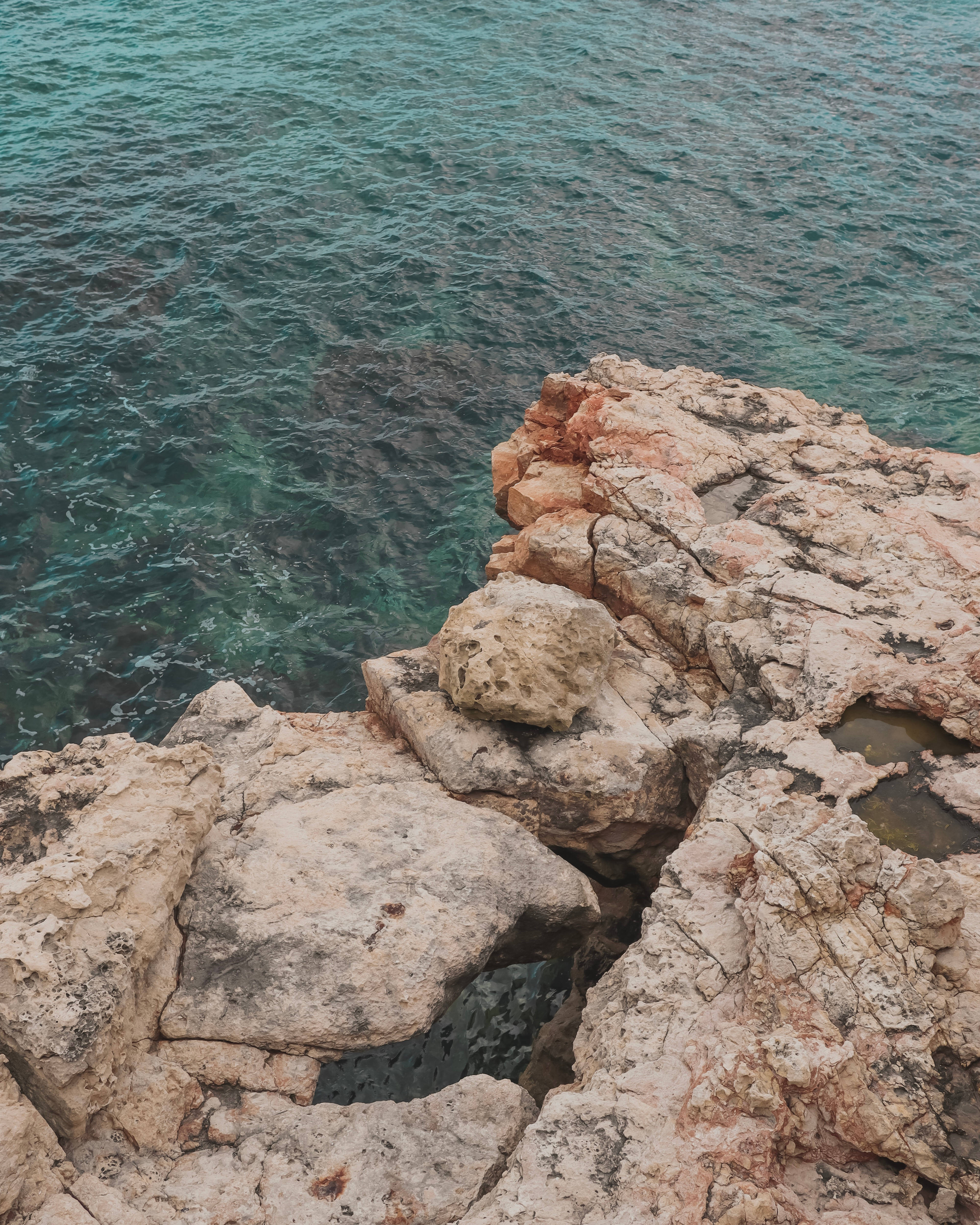 Malta 桌布 壁紙 — 粗糙紋理的懸崖帶有粉紅色岩石，在陽光普照的海岸場景中與碧綠的海浪相遇。