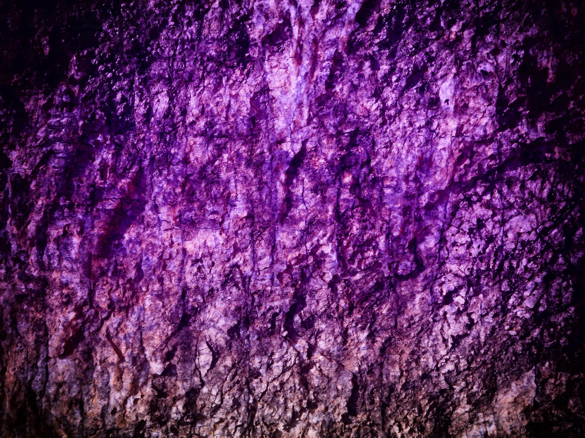 Purple stone texture 壁紙 — 粗糙紋理表面的特寫，沐浴在深紫色光線中，黑暗陰影凸顯其崎嶇輪廓。