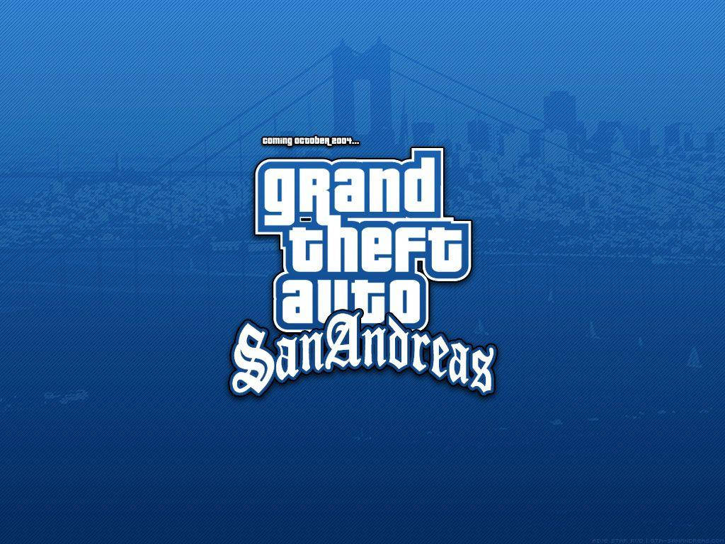 GTA 聖安地列斯 桌布 壁紙 — 粗體白色 'Grand Theft Auto San Andreas' 標誌，帶有 'coming october 2004' 文字，居中於帶有紋理的藍色背景上，並有模糊的城市天際線剪影。