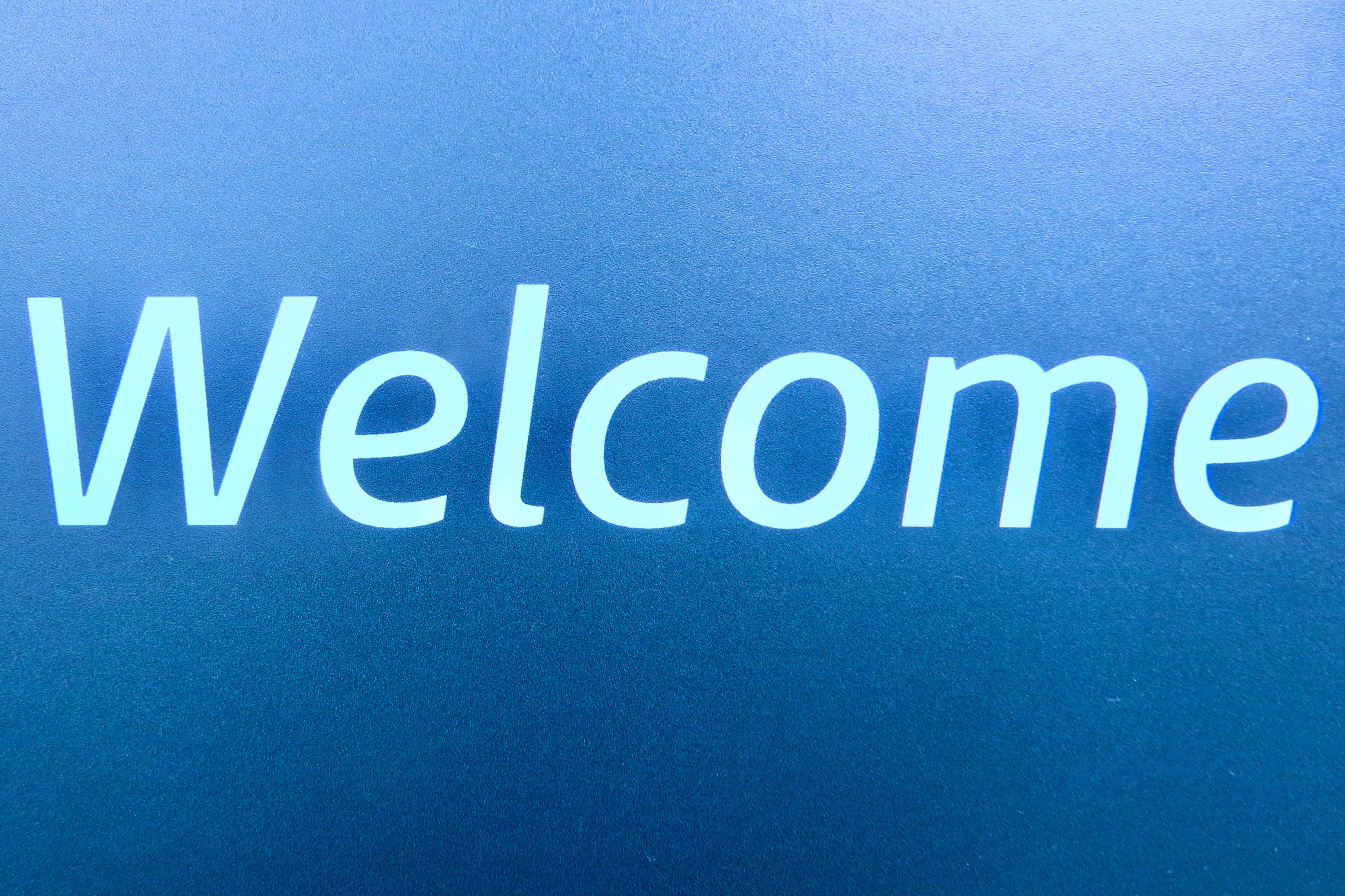 Welcome 桌布 壁紙 — 粗體白色「歡迎」文字在帶有紋理的漸變藍色背景上柔和發光。