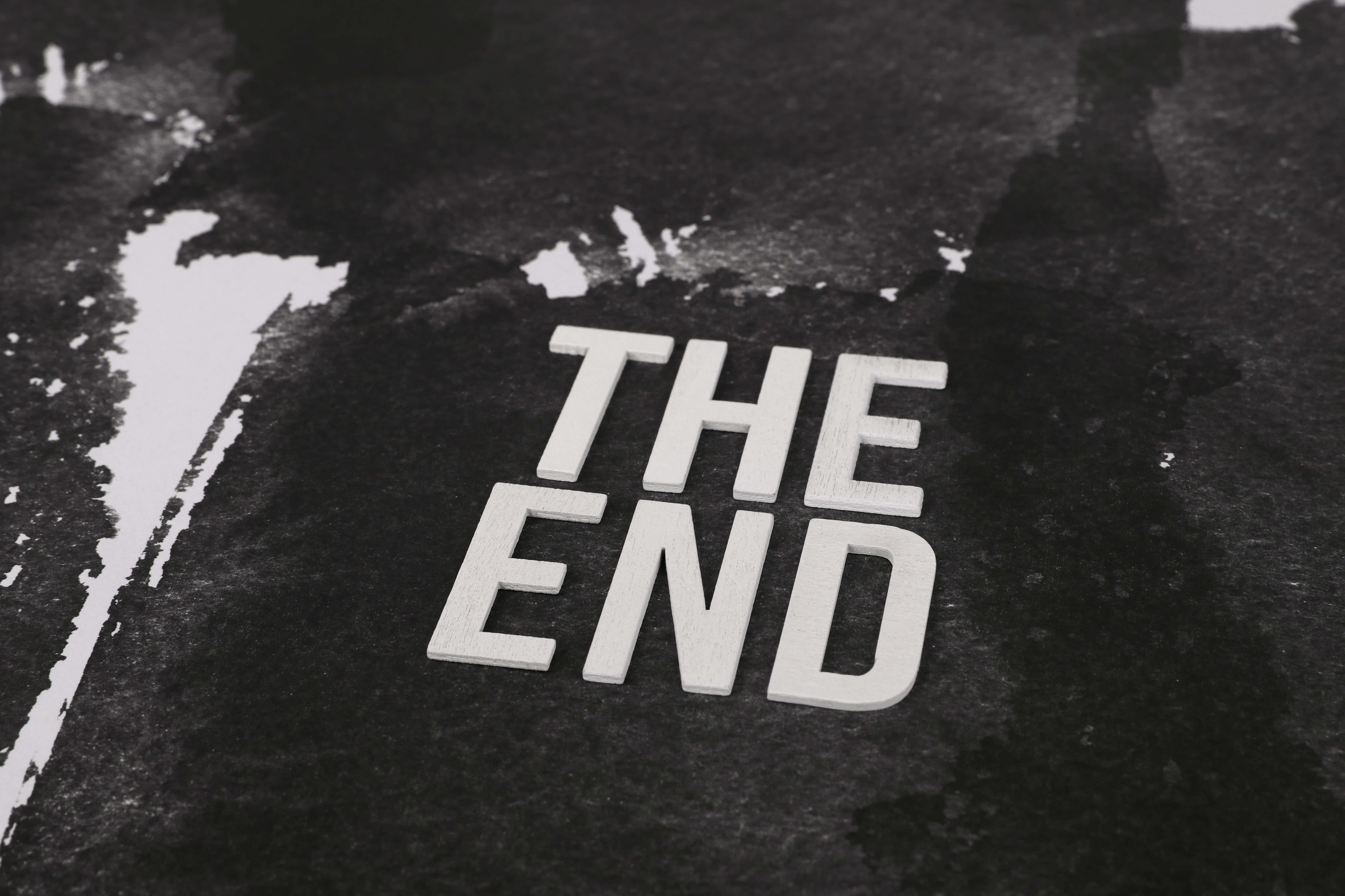 the end 桌布 壁紙 — 粗體白色3D字母拼出'THE END'，放置在帶紋理的深色grunge表面上，並有醒目的白色油漆飛濺。