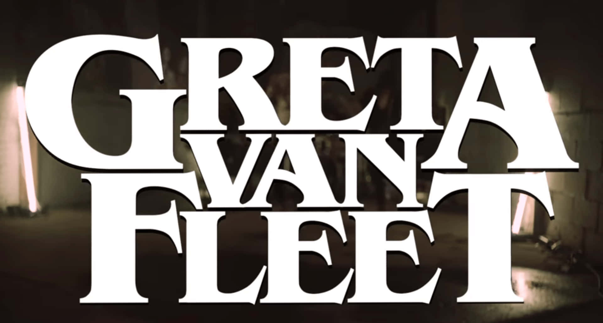 band 桌布 壁紙 — 粗體白色文字拼出 Greta Van Fleet，主導著昏暗的工業背景，帶有發光的垂直燈光。