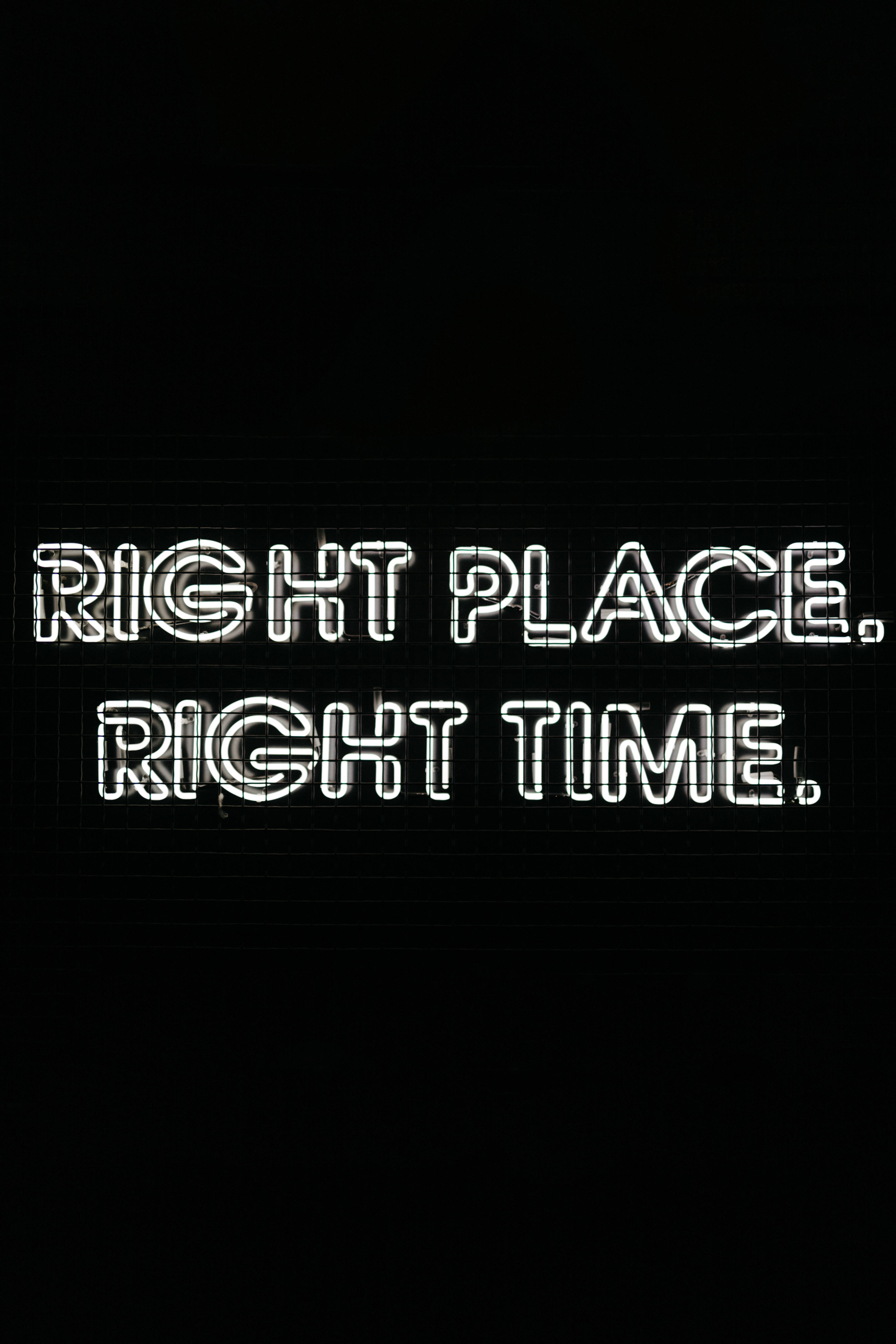 語錄 桌布 壁紙 — 粗體白色霓虹燈文字「right place right time」在帶有微妙網格線的純黑色背景上發光。