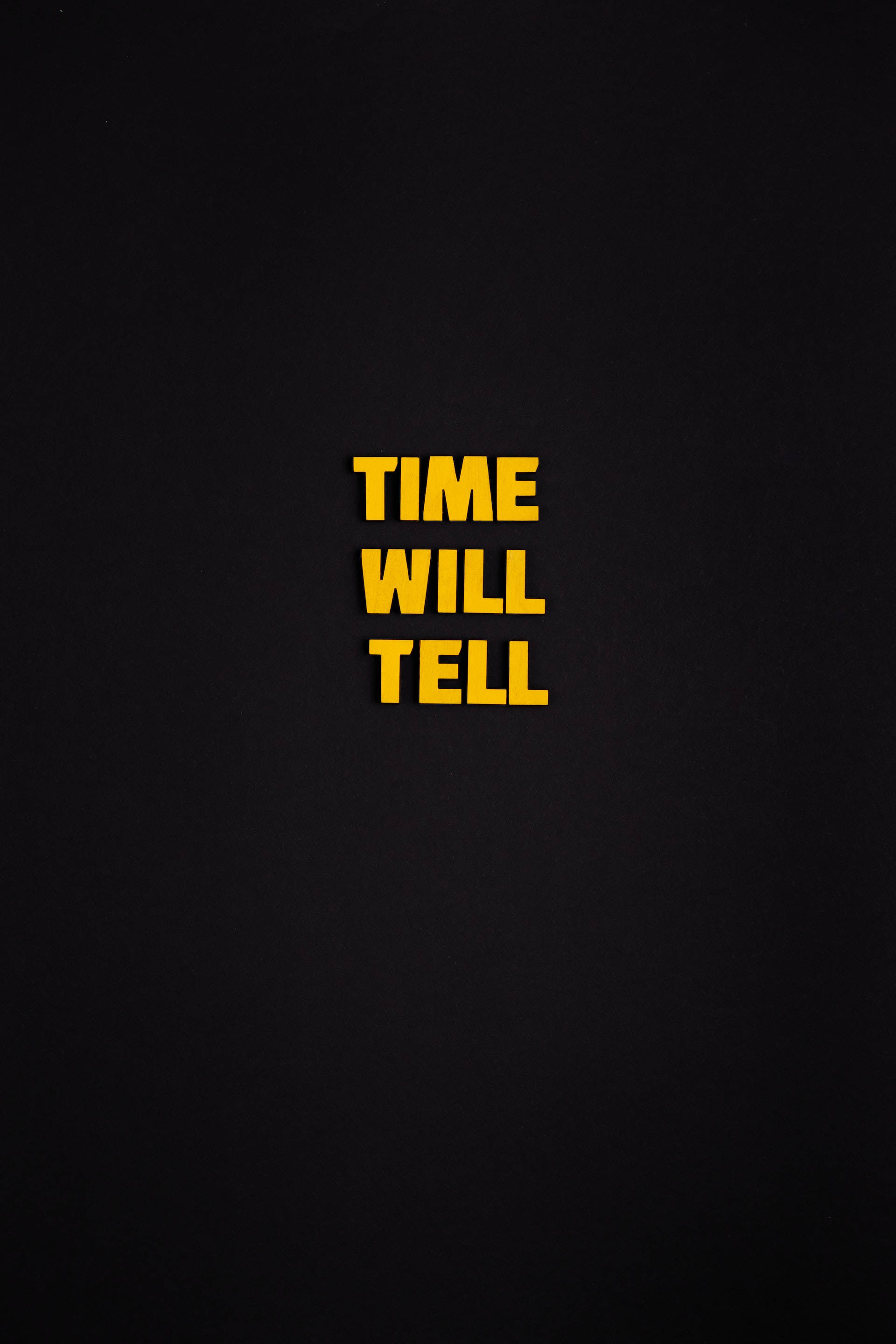 黑色電話 桌布 壁紙 — 粗體黃色文字 time will tell 居中顯示在樸素的黑色紋理背景上。