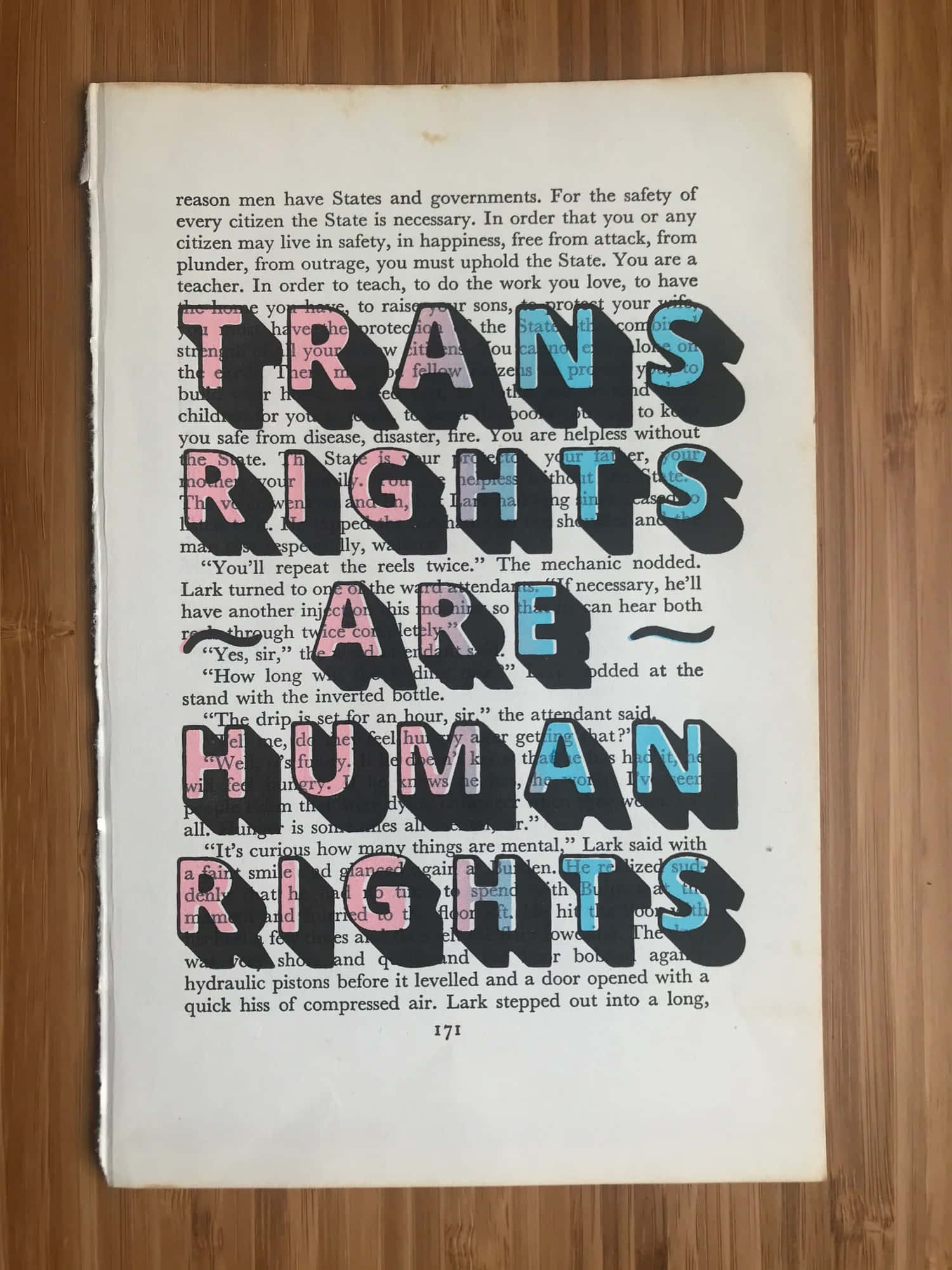 transgender 桌布 壁紙 — 粗體黑色文字在復古書頁上宣告「TRANS RIGHTS ARE HUMAN RIGHTS」，書頁置於木質表面。