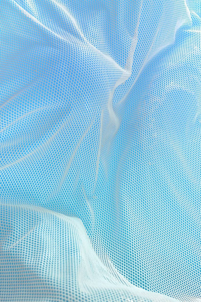 Aesthetic Baby Blue 桌布 壁紙 — 精緻白色網狀布料的特寫，覆蓋在柔軟的藍色背景上，帶有輕柔的褶皺和光線反射。