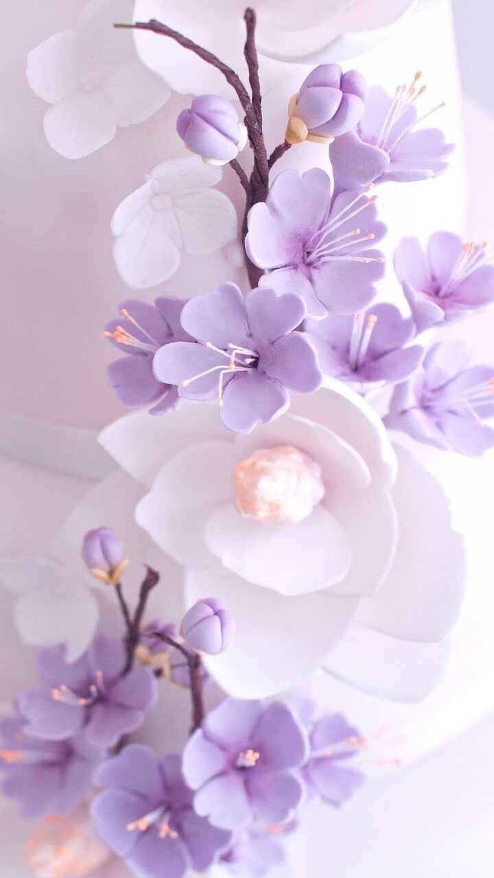 Purple Flowers 桌布 壁紙 — 精緻的淡紫色和白色紙花，帶有金色雄蕊，在粉彩粉紅色背景上柔和綻放。