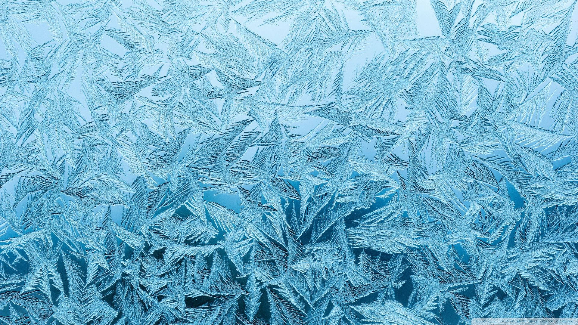 冰雪奇緣 桌布 壁紙 — 精緻的藍色霜晶在窗玻璃上形成複雜的星形圖案，背景是柔和的漸變天空。