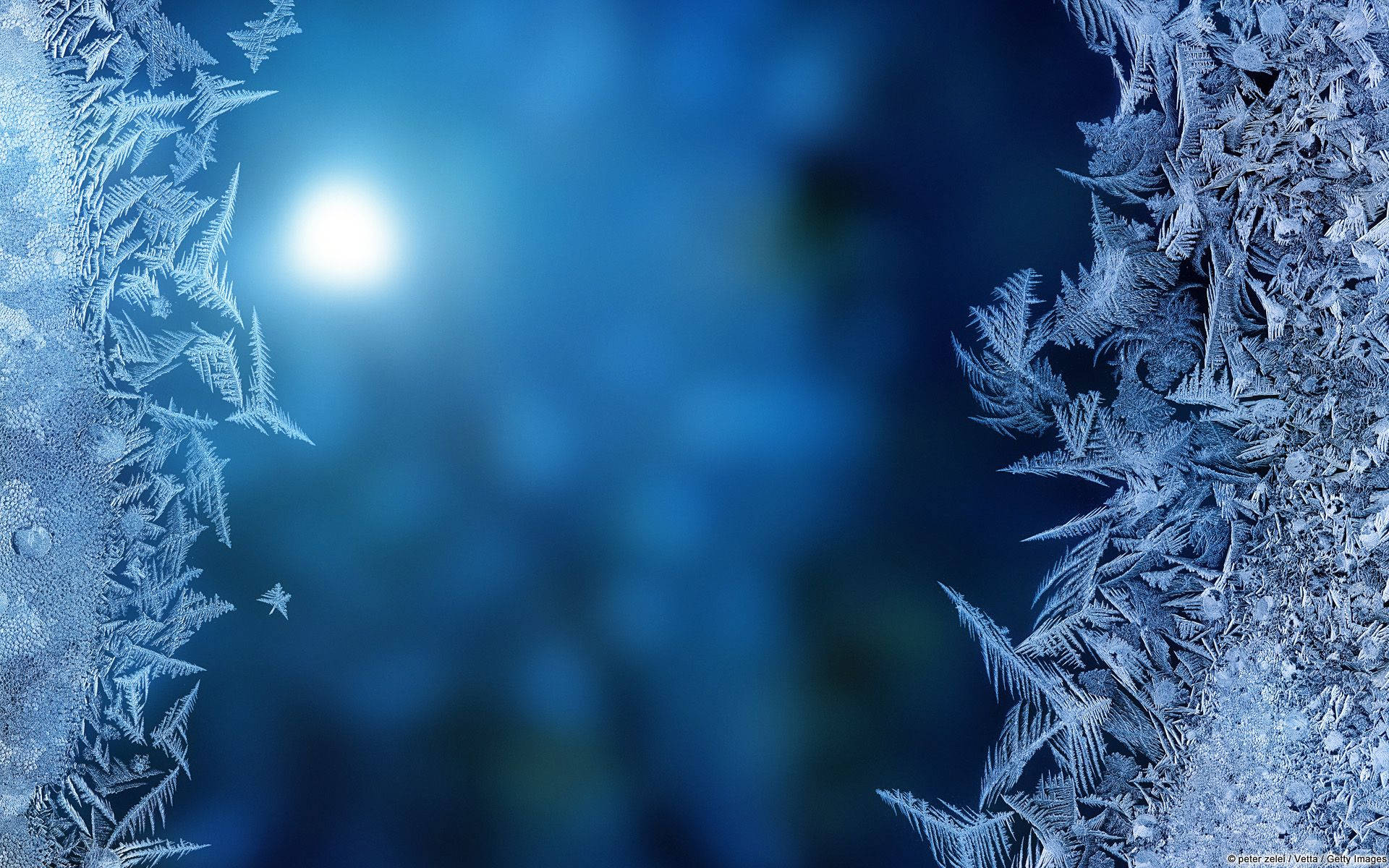 霜花圖案在涼爽的藍色夜景中圍繞著發光的月亮。 — Microsoft 壁紙