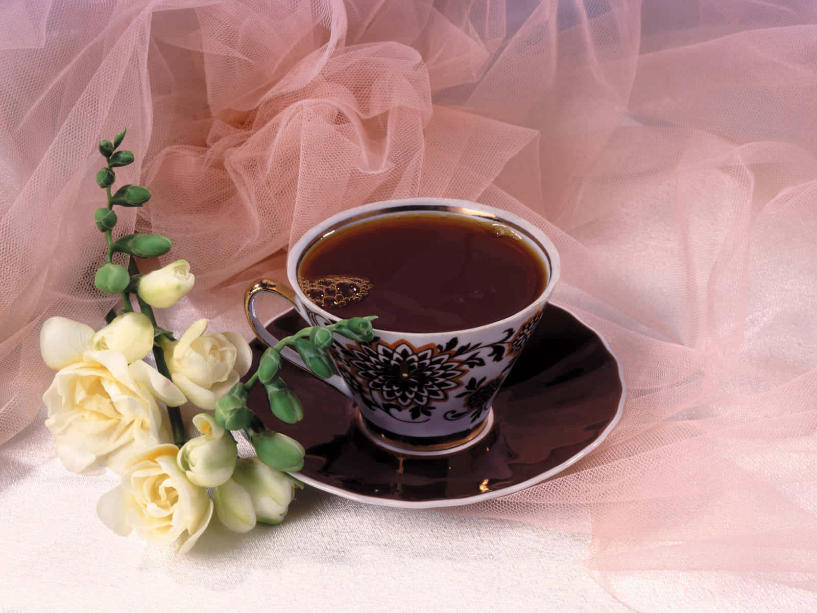 Floral Tea 桌布 壁紙 — 精緻華麗的茶杯盛滿深色茶，旁邊放著淡黃玫瑰，背景是柔軟的粉紅色薄紗。