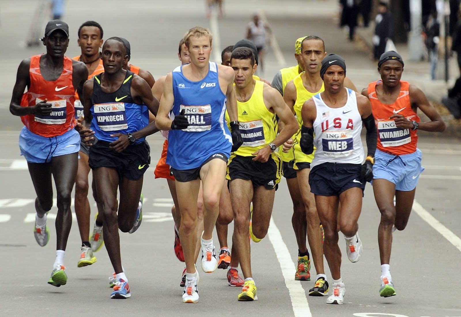 Marathon 桌布 壁紙 — 精英馬拉松跑者穿著鮮豔的比賽裝備，在競爭激烈的比賽中沿著鋪砌的城市街道全力衝刺。