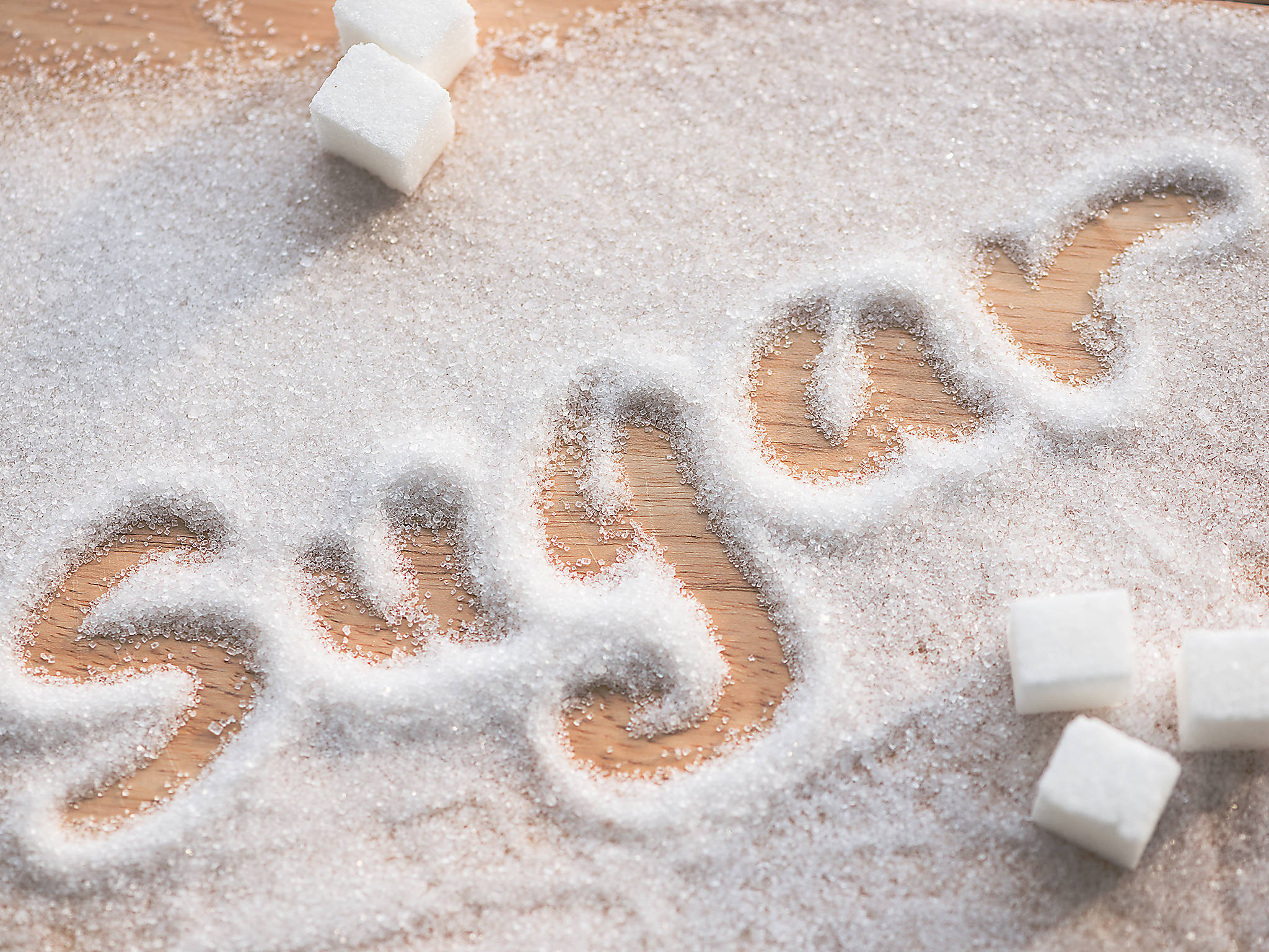 Sugar 桌布 壁紙 — 「糖」這個字用砂糖寫在木質表面上，周圍散落著方糖。