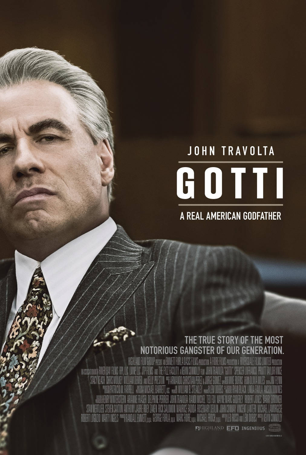 Gotti 桌布 壁紙 — 約翰·屈伏塔飾演的高蒂身穿細條紋西裝，在昏暗的法庭場景中凝視著。