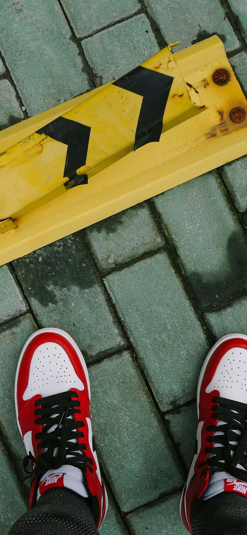 Sneaker 桌布 壁紙 — 紅、白、黑色運動鞋站在濕綠色磚塊上，旁邊有黃色警示欄杆。