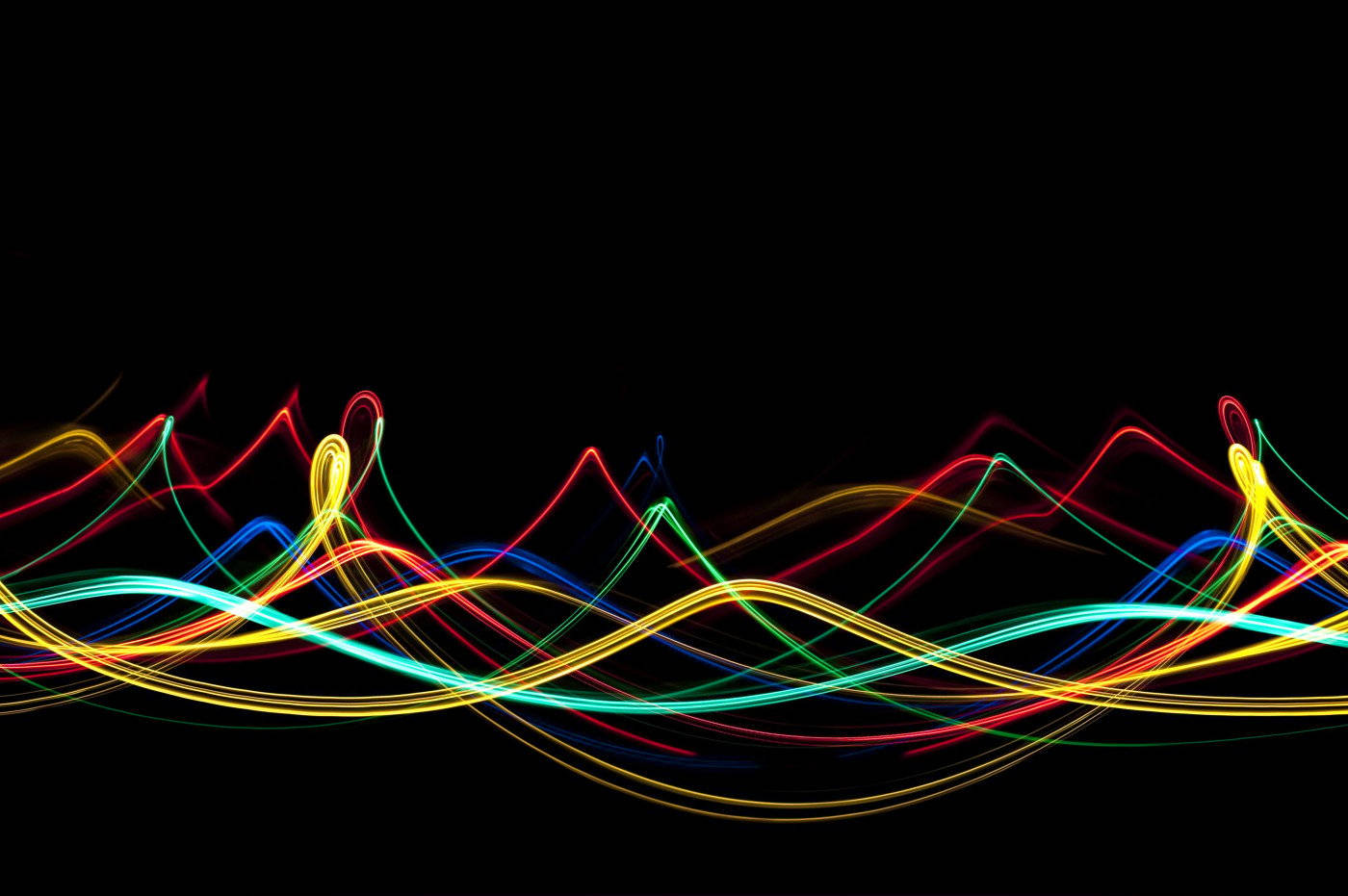 Neon Light 桌布 壁紙 — 紅、黃、綠、藍色的鮮豔霓虹光軌，像舞動的能量般在黑色背景上流動。