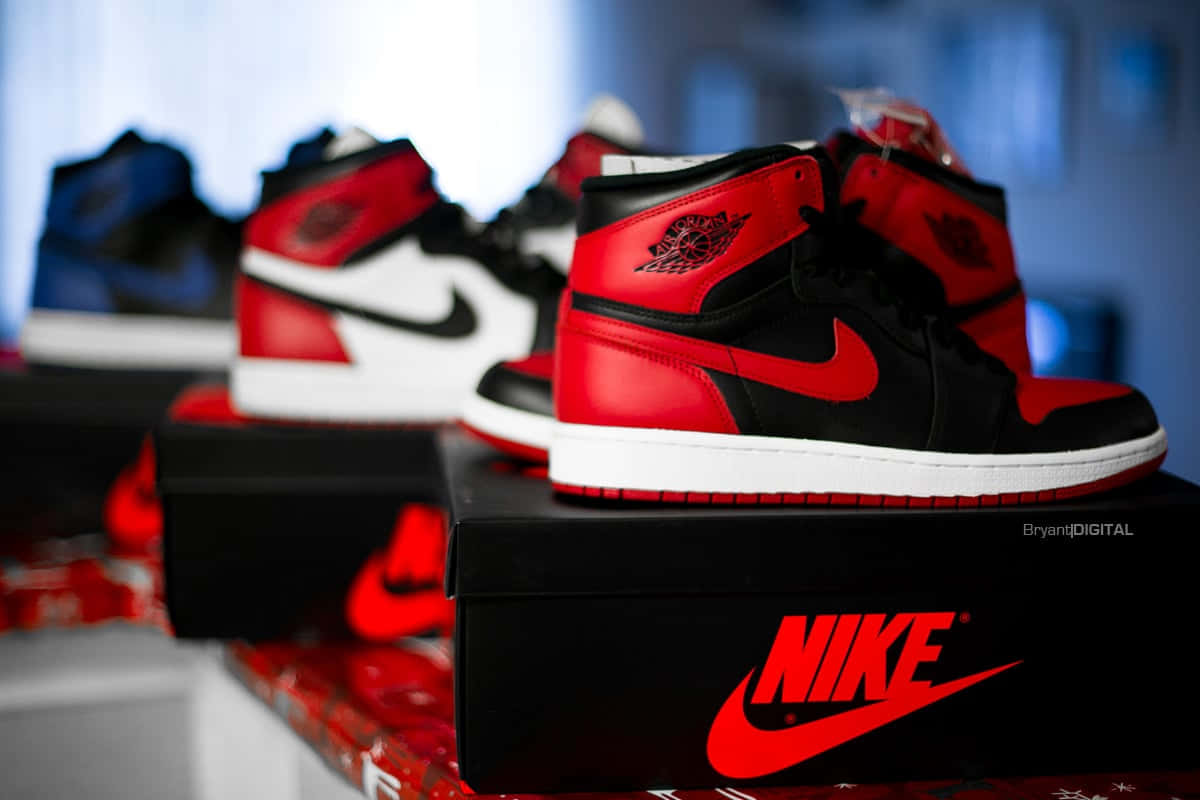 Air Jordan 1 桌布 壁紙 — 紅、黑、白色Jordan 1運動鞋展示在品牌盒上，背景燈光模糊。
