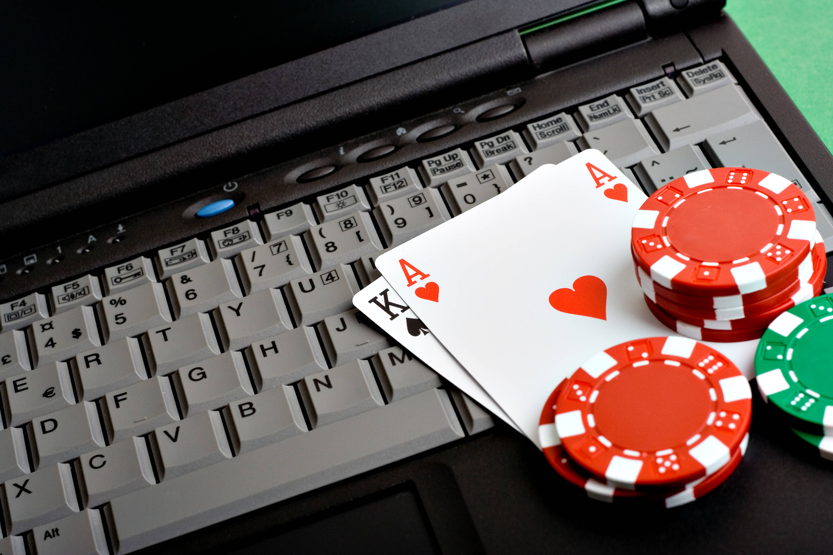 Poker Table 桌布 壁紙 — 紅心A和黑桃K牌放在筆記型電腦鍵盤上的紅色和綠色籌碼上。