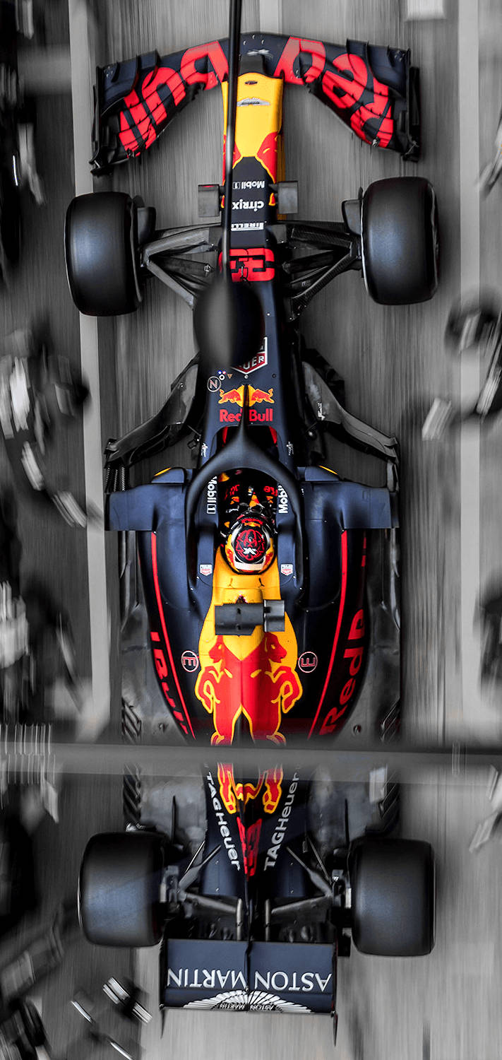 Verstappen 桌布 壁紙 — 紅牛車隊一級方程式賽車在賽道上高速行駛的鳥瞰圖，帶有動態模糊和鏡面反射效果。