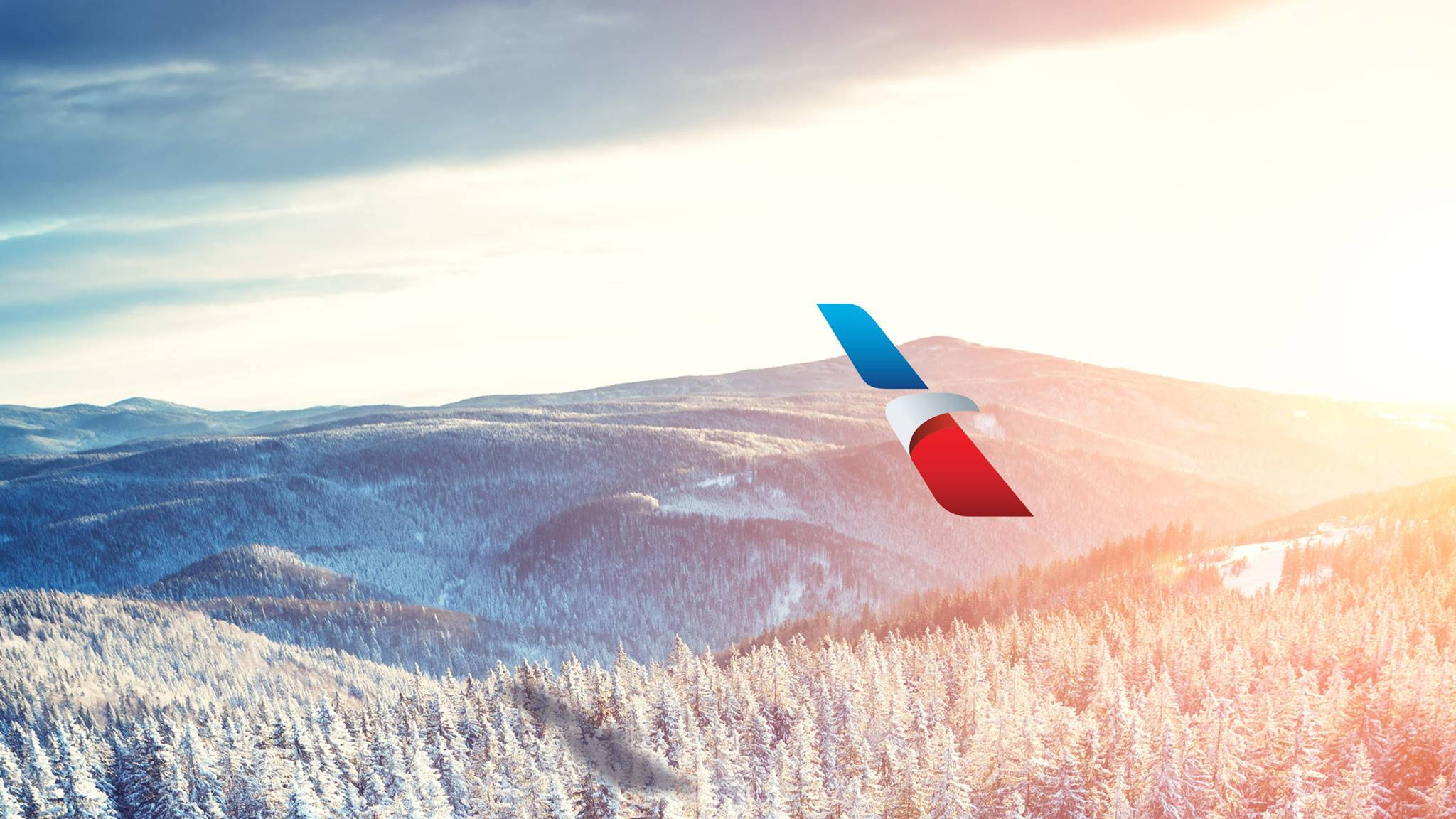 Airlines 桌布 壁紙 — 紅白藍塗裝的飛機尾部在金色日落時分翱翔於白雪覆蓋的松林和連綿山脈之上。