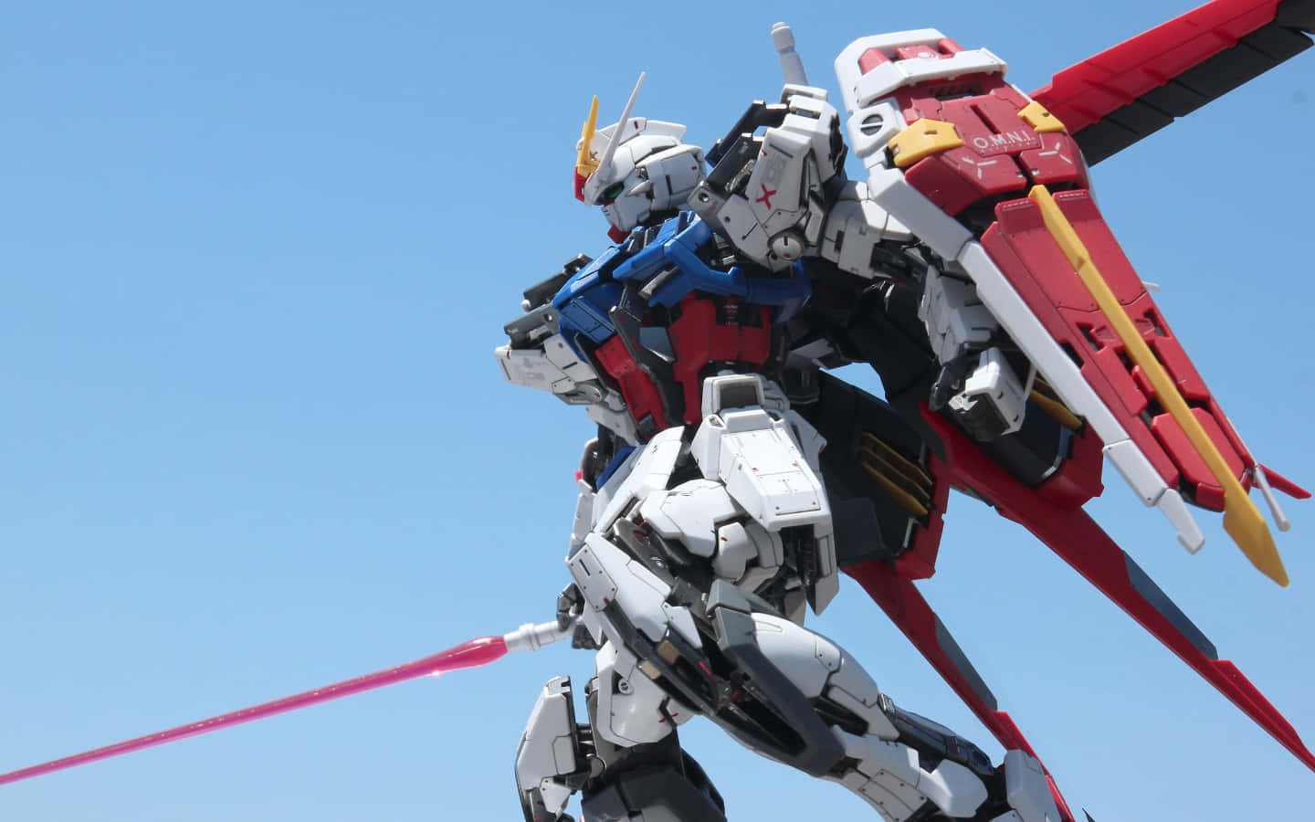 Gundam Desktop 桌布 壁紙 — 紅白藍色的鋼彈模型在清澈的藍天下擺出姿勢，發射粉紅色光束軍刀。