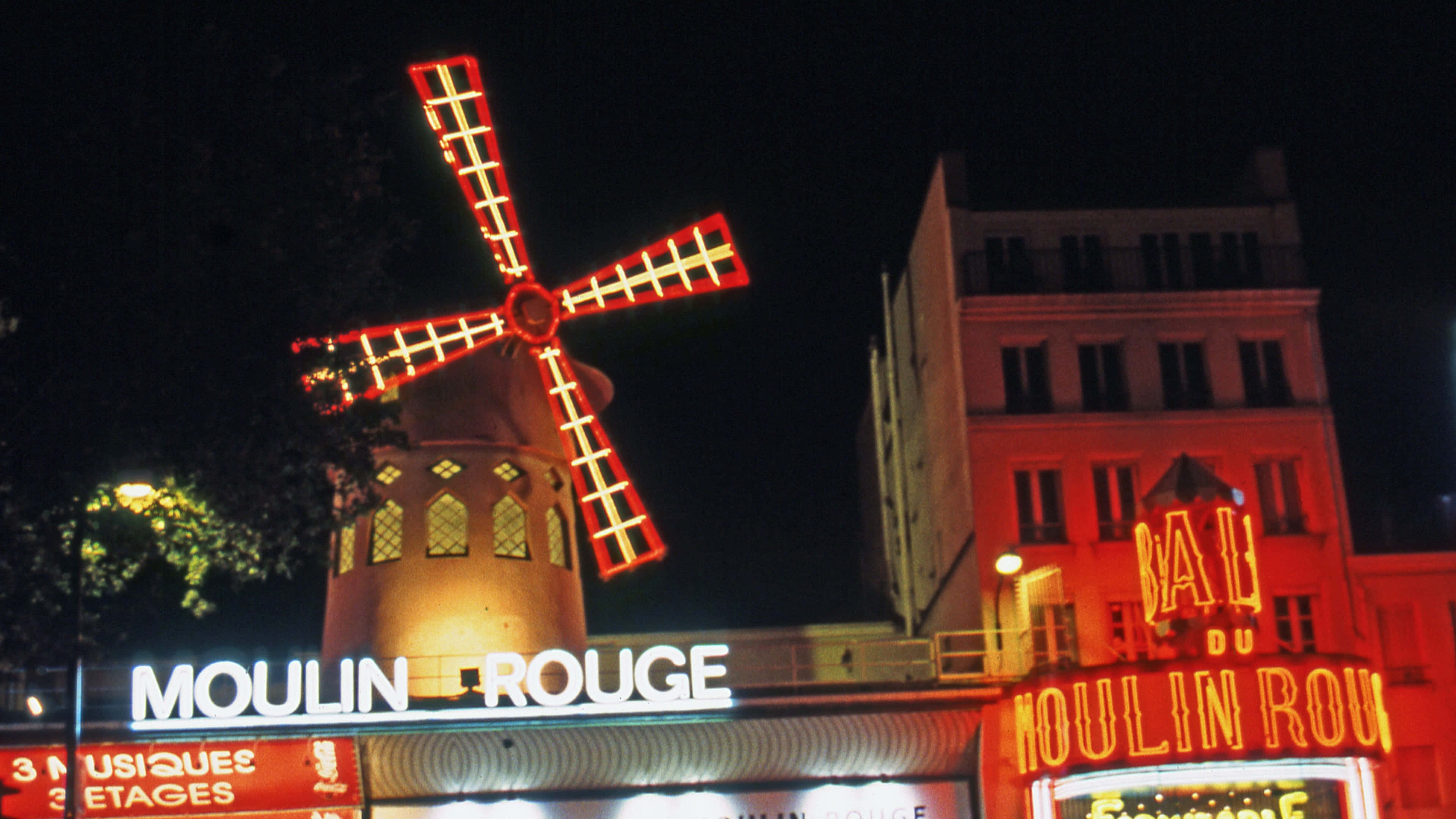 moulin rouge 桌布 壁紙 — 紅磨坊風車在漆黑的巴黎夜空下閃耀紅光的迷人夜景。