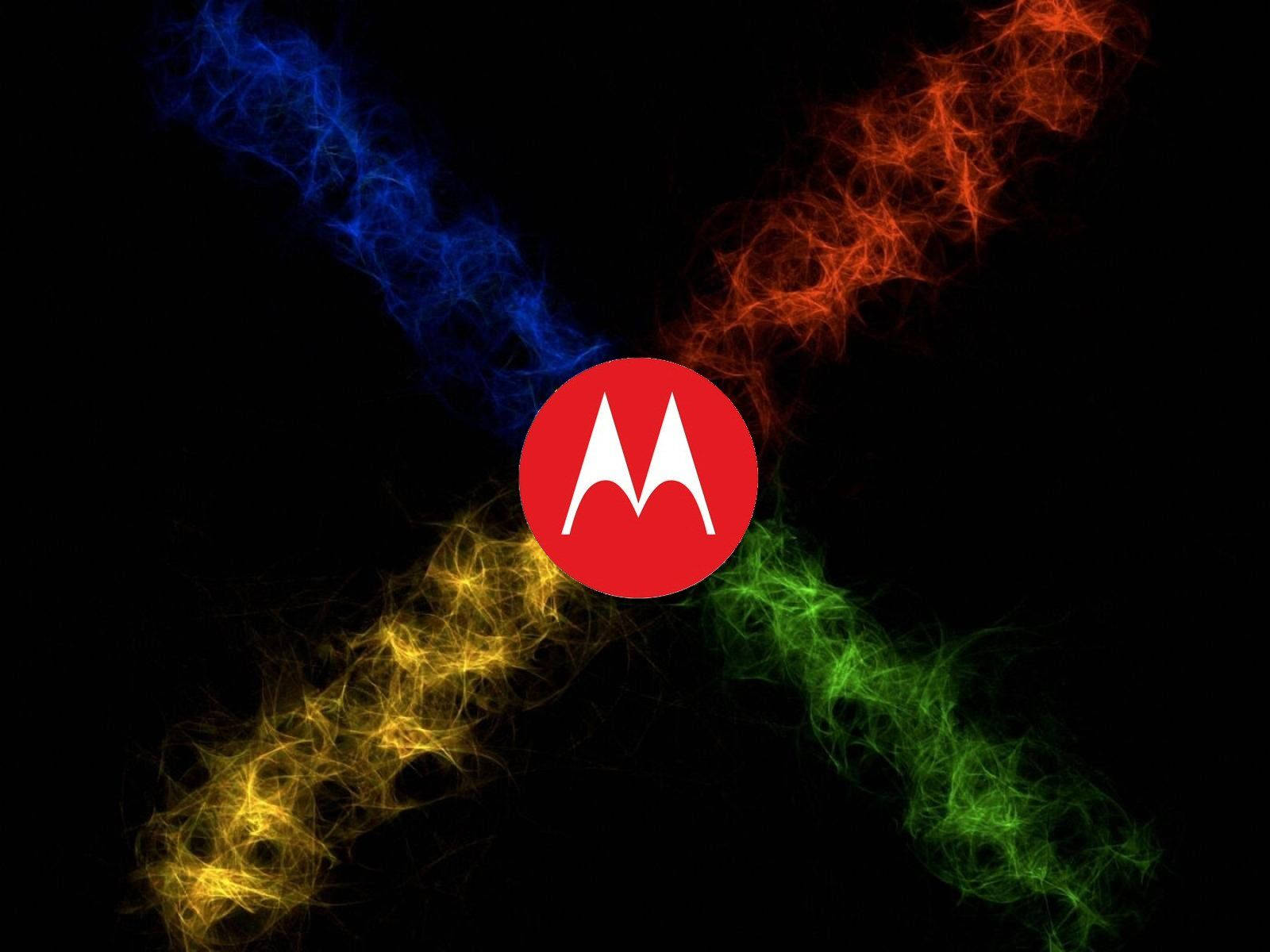 摩托羅拉 桌布 壁紙 — 紅色 Motorola 標誌置中於黑色背景上，四條彩色能量流以藍色、橙色、黃色和綠色向外輻射。