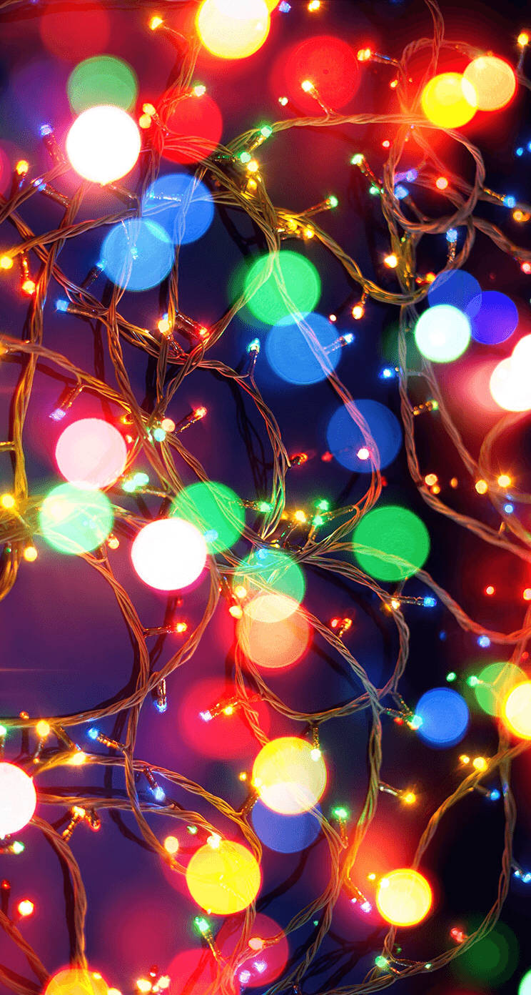 Christmas Lights Aesthetic 桌布 壁紙 — 紅色、綠色、藍色和黃色的鮮豔散景燈光在黑暗背景中與纏繞的繩索一起發光。
