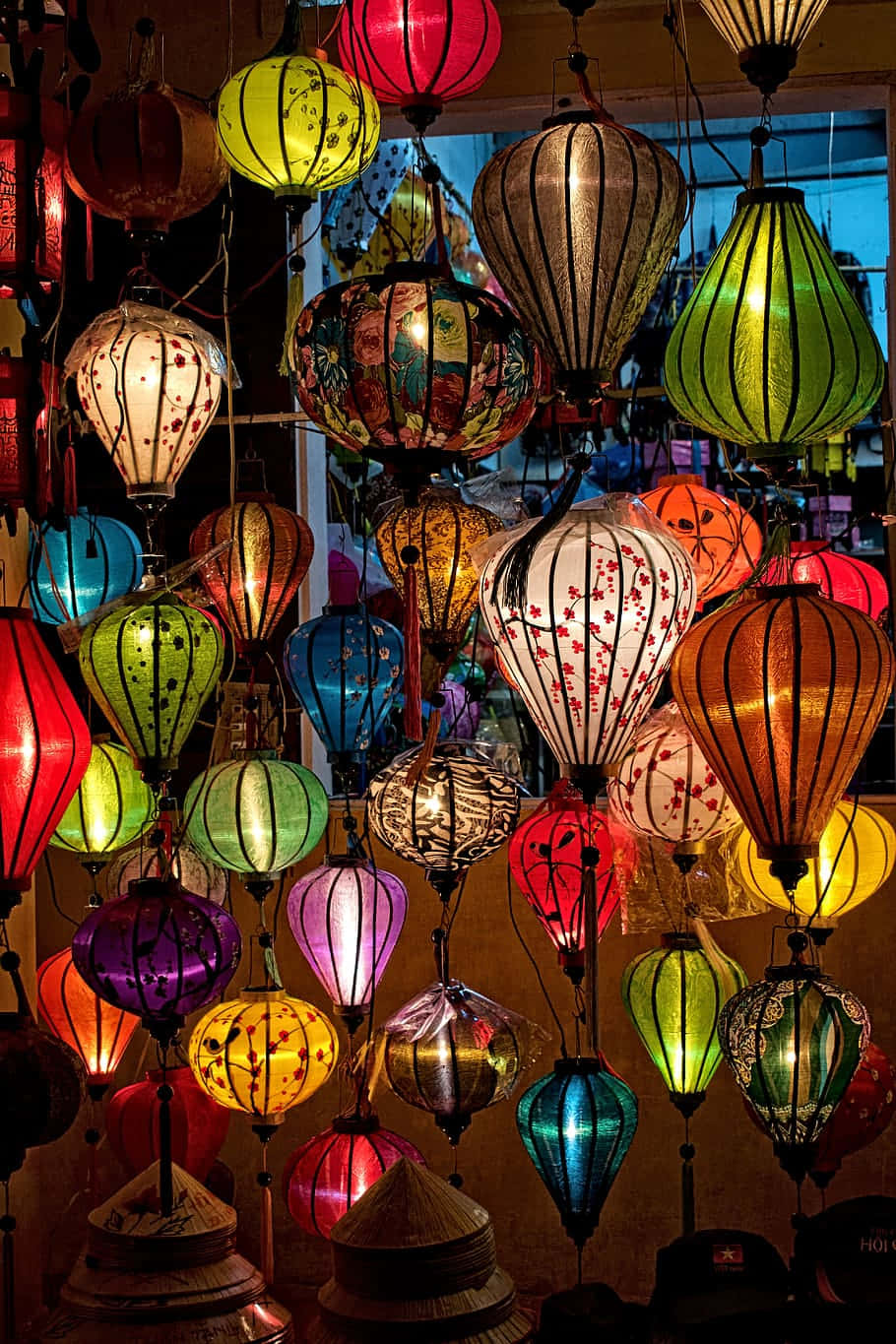 Lantern 桌布 壁紙 — 紅色、綠色、藍色和黃色的鮮豔發光紙燈籠密密麻麻地掛在燈光昏暗的商店裡，營造出溫暖的節日氣氛。