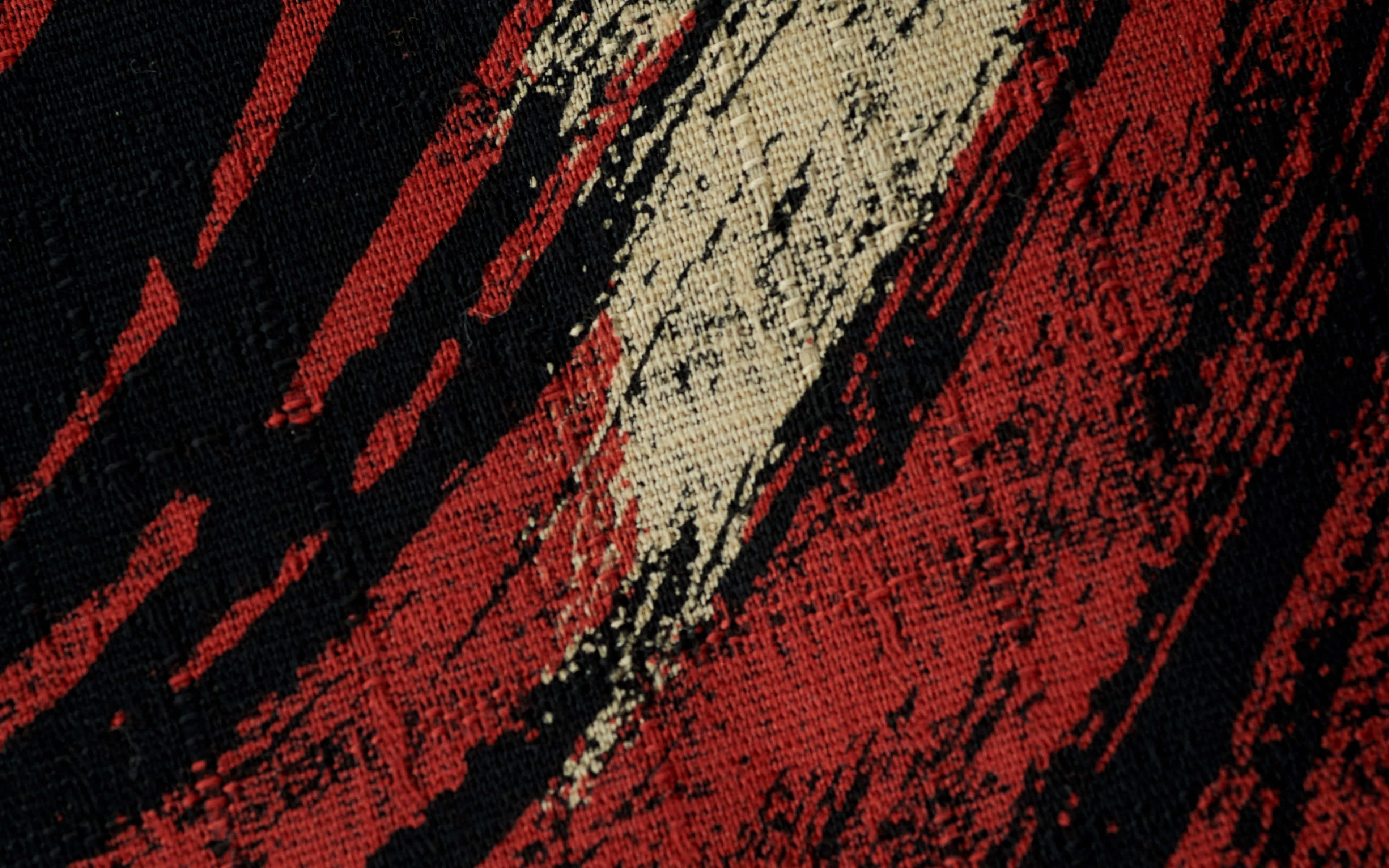 Textured 桌布 壁紙 — 紅色、黑色和奶油色的粗體對角線筆觸在紋理織物表面上延伸。