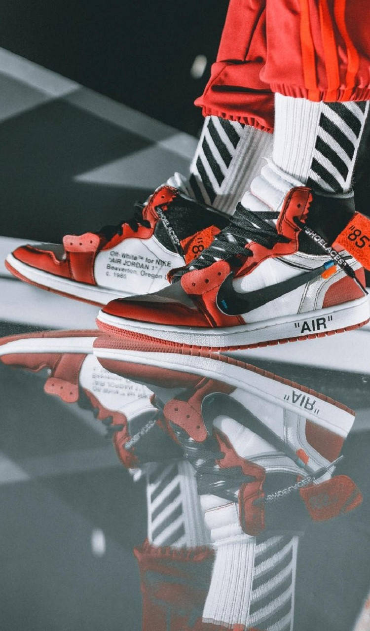 Glass Texture 桌布 壁紙 — 紅色、黑色和白色 Off-White x Air Jordan 1 運動鞋配條紋襪子在光澤地板上的特寫倒影。