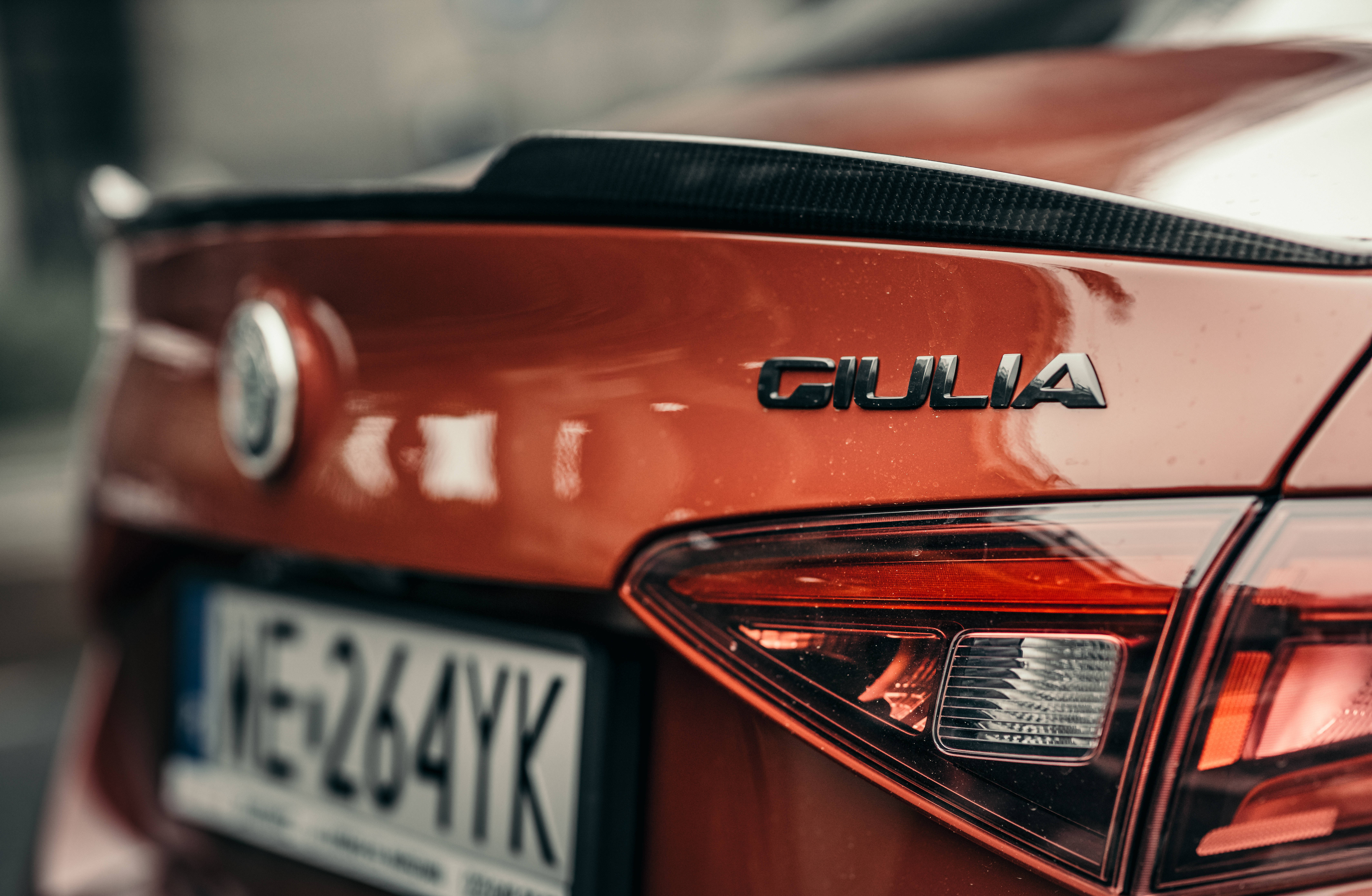 愛快羅密歐 桌布 壁紙 — 紅色Alfa Romeo Giulia車尾特寫，展現其時尚尾燈和碳纖維尾翼。