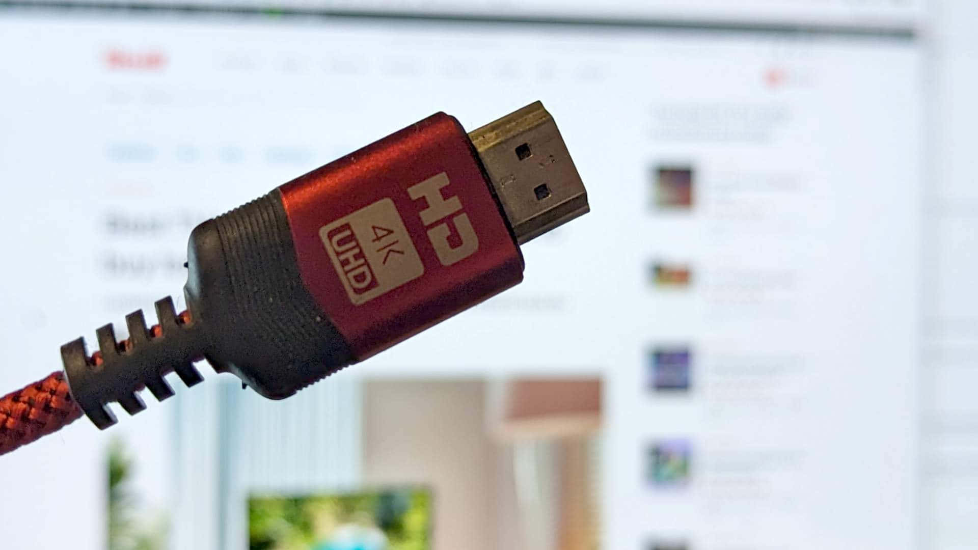 Hdmi 桌布 壁紙 — 紅色HDMI線連接器特寫，帶有4K UHD標籤，背景是模糊的電腦螢幕，顯示媒體縮圖。