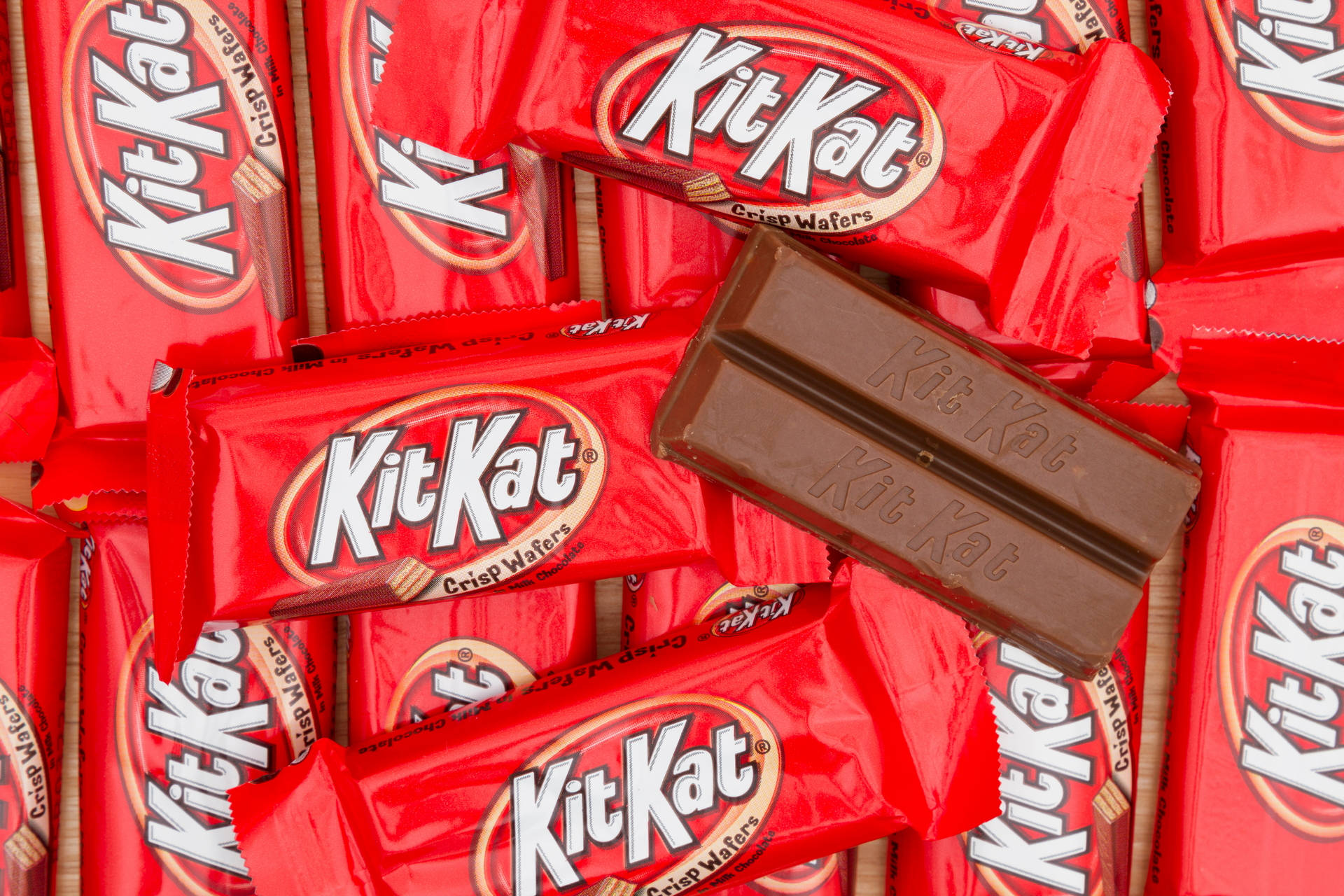 Chocolate 桌布 壁紙 — 紅色KitKat包裝紙和破碎巧克力棒的近距離特寫，露出脆脆的威化餅。