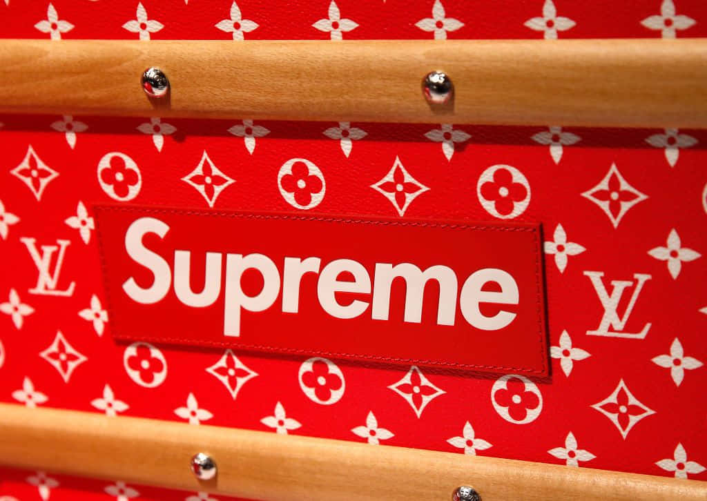 supreme 桌布 壁紙 — 紅色Louis Vuitton monogram行李箱的特寫，帶有Supreme標誌貼片和木製把手。
