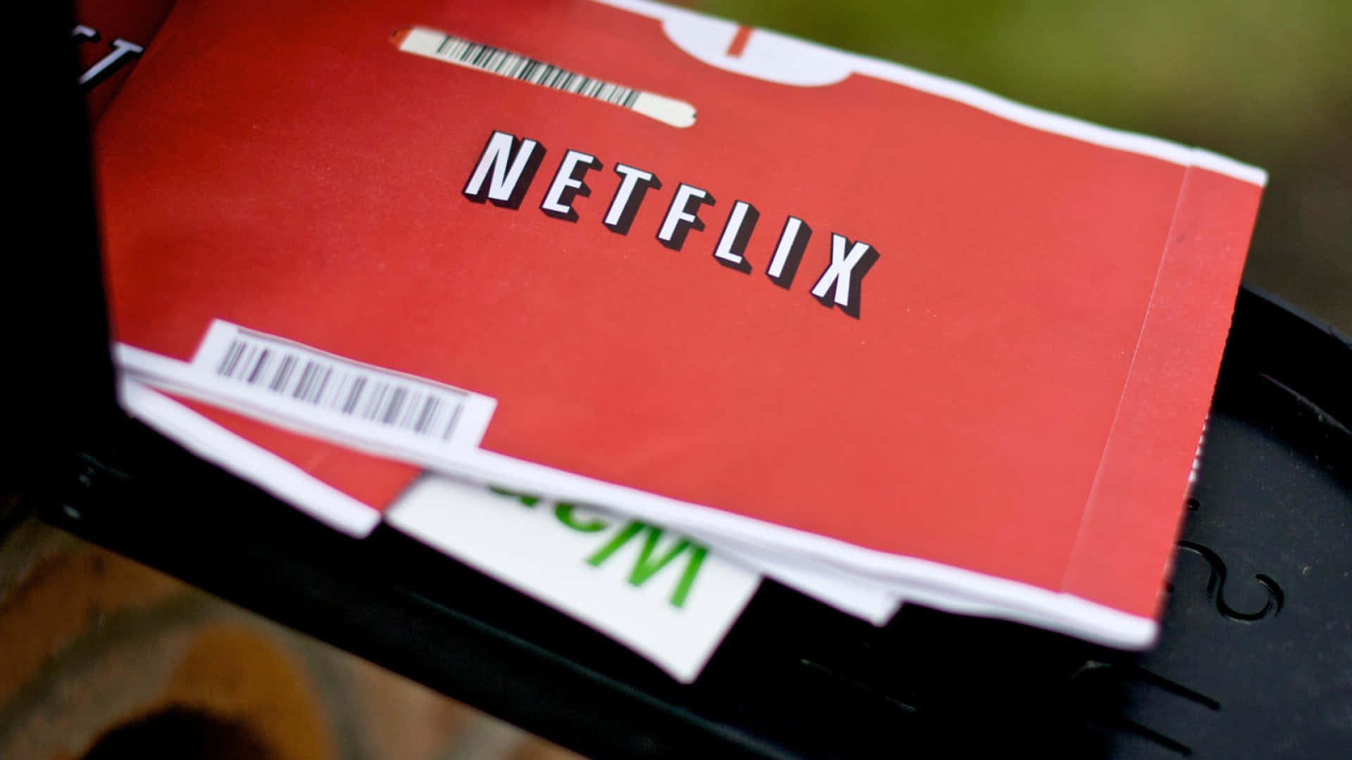 Netflix 桌布 壁紙 — 紅色Netflix DVD盒特寫，帶有條碼，放置在黑色塑膠表面上。