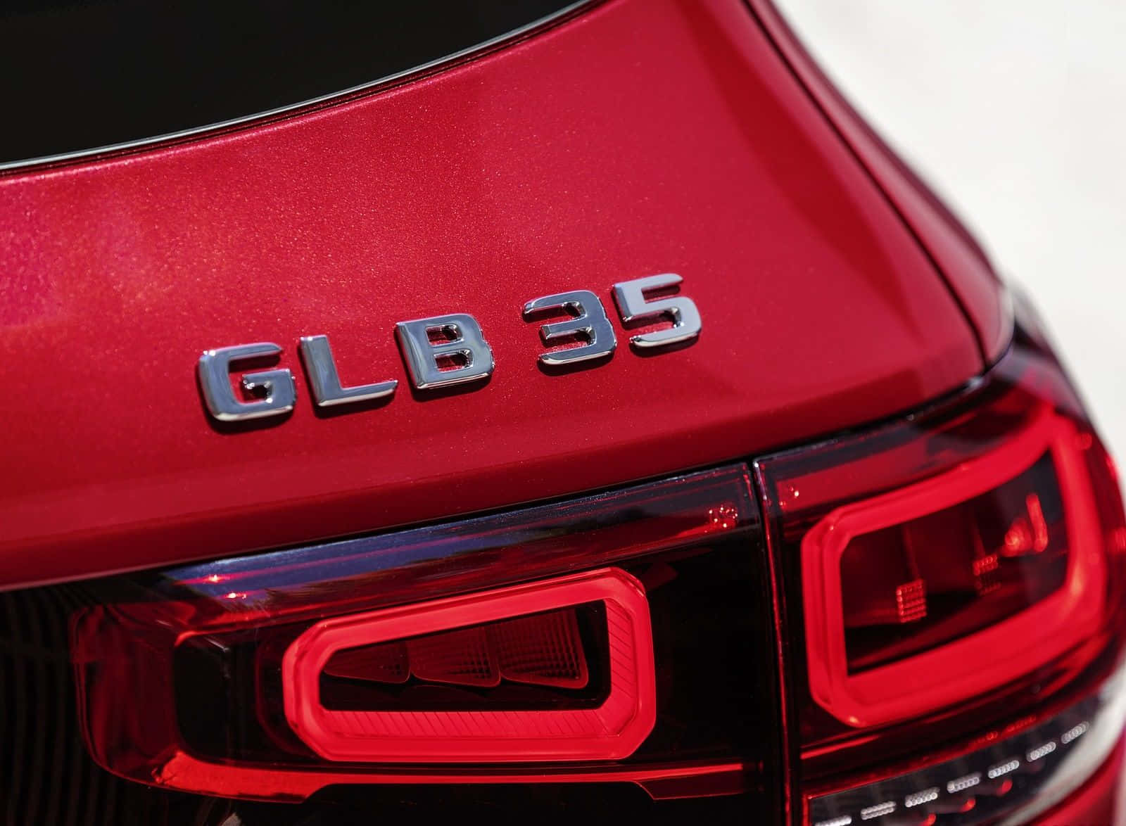 Red Metallic 桌布 壁紙 — 紅色光面車尾箱徽章特寫，上面寫著 GLB 35，配以時尚尾燈反射光線。