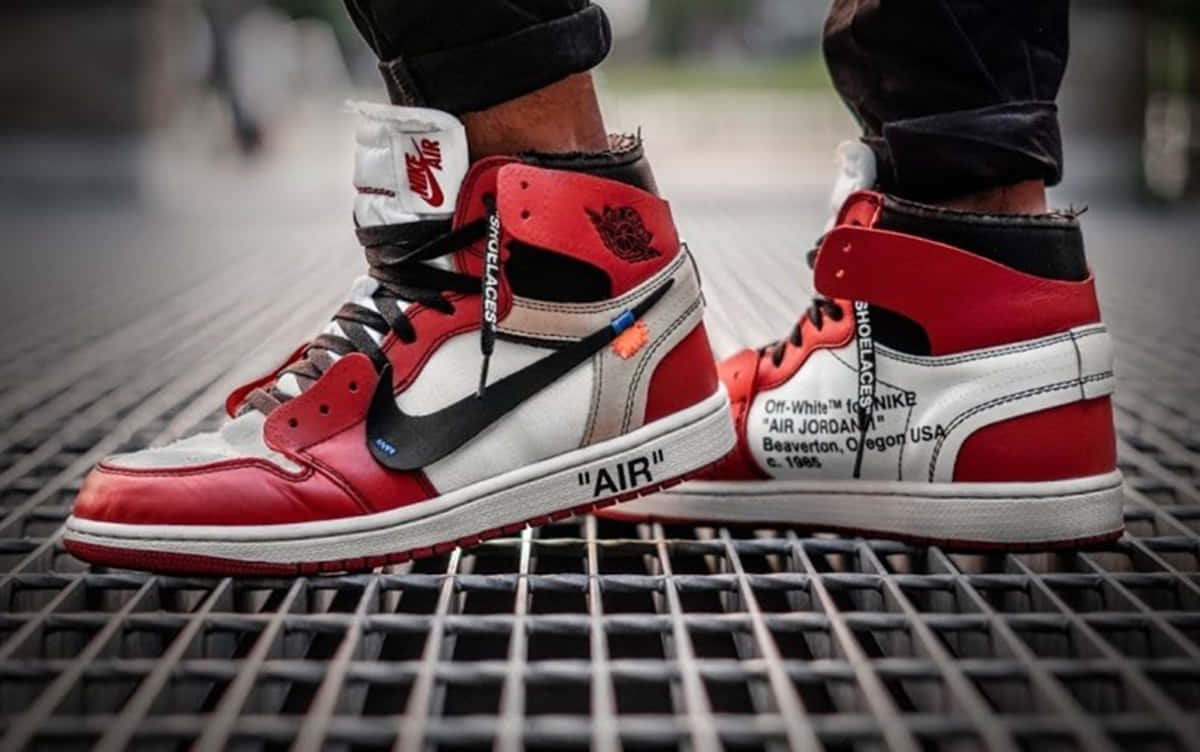 Off White Jordan 1 桌布 壁紙 — 紅色和白色 Off-White x Air Jordan 1 運動鞋在金屬格柵上的特寫，背景為模糊的城市景觀。