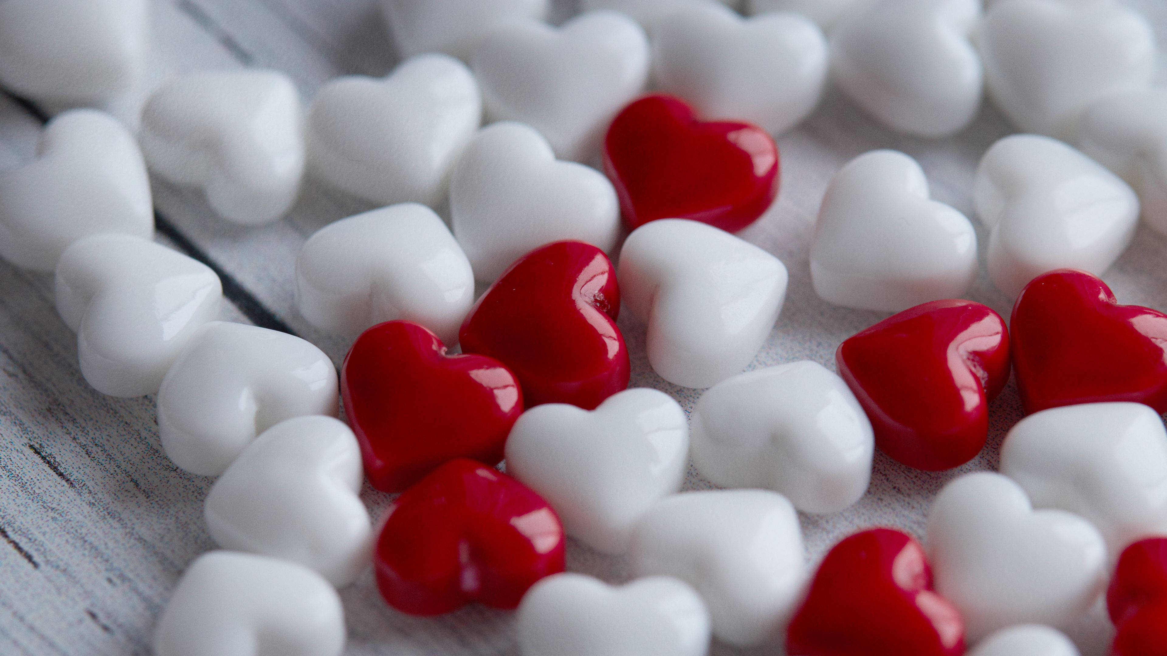 Happy Valentines Day 桌布 壁紙 — 紅色和白色光澤的心形糖果散落在風化的木質表面上。