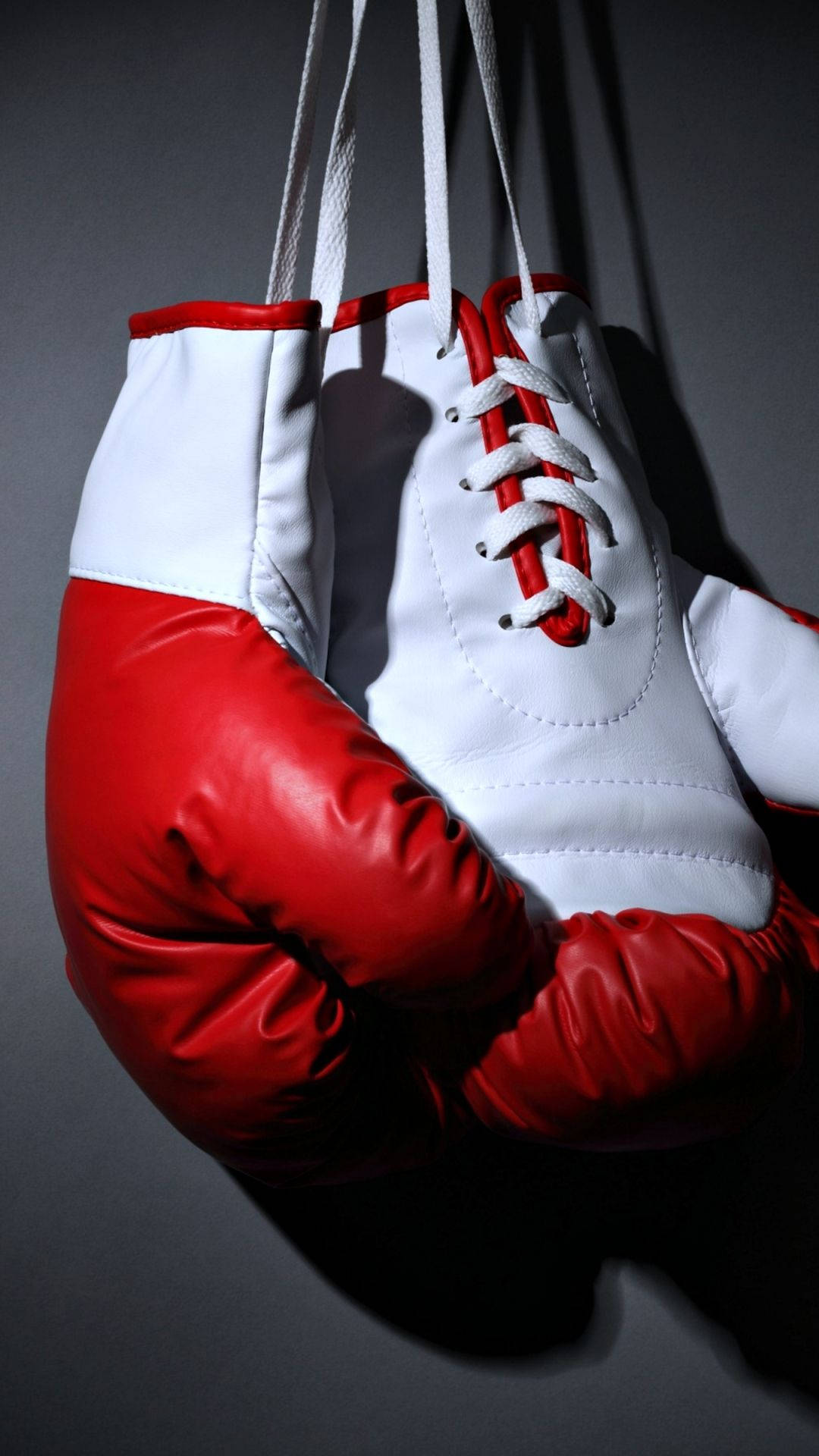 Boxing 桌布 壁紙 — 紅色和白色的拳擊手套懸掛在深灰色背景上，帶有戲劇性的燈光。