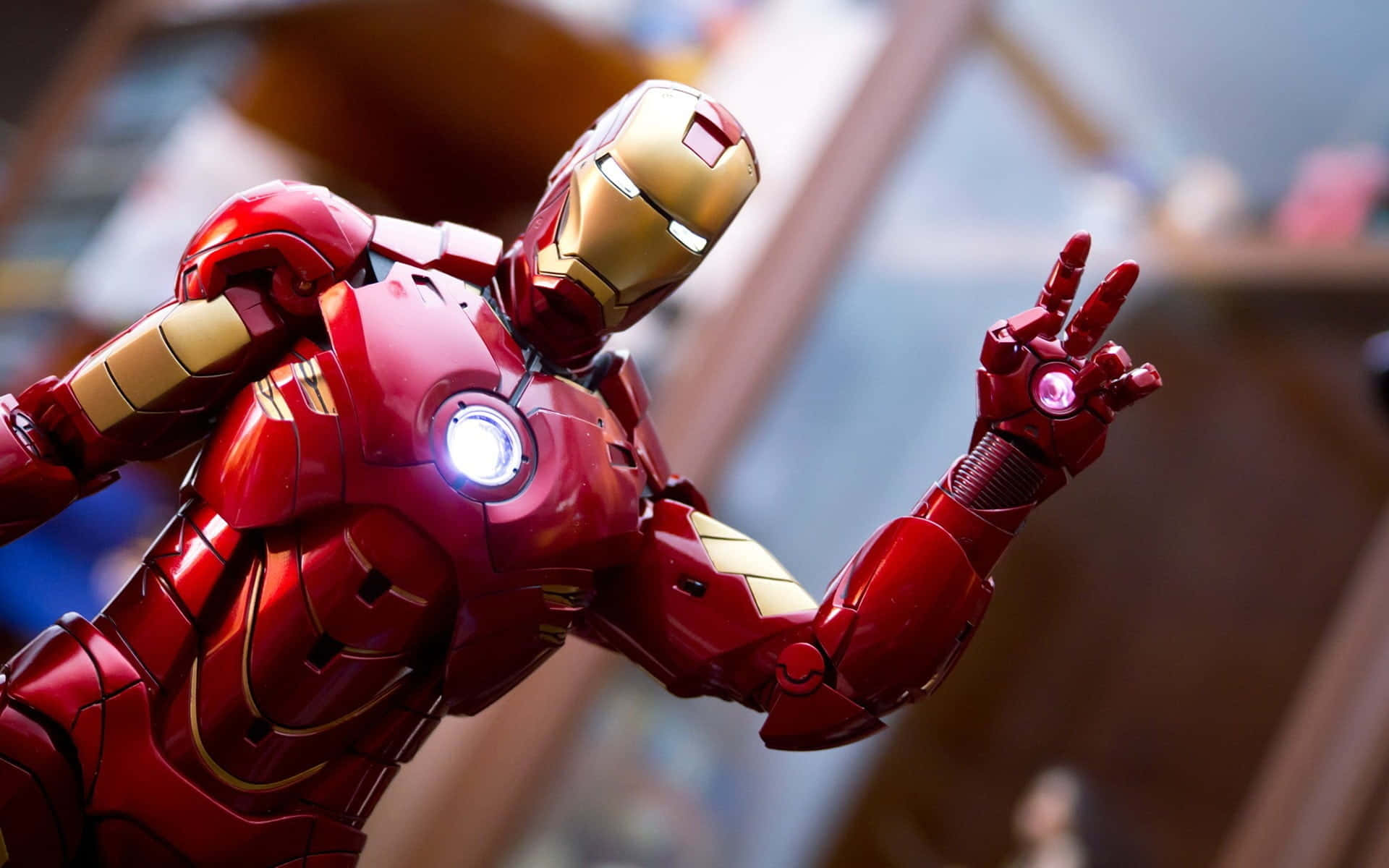 Iron Man Action Figures 桌布 壁紙 — 紅色和金色鋼鐵人套裝的特寫，帶有發光的弧形反應器和斥力手勢。