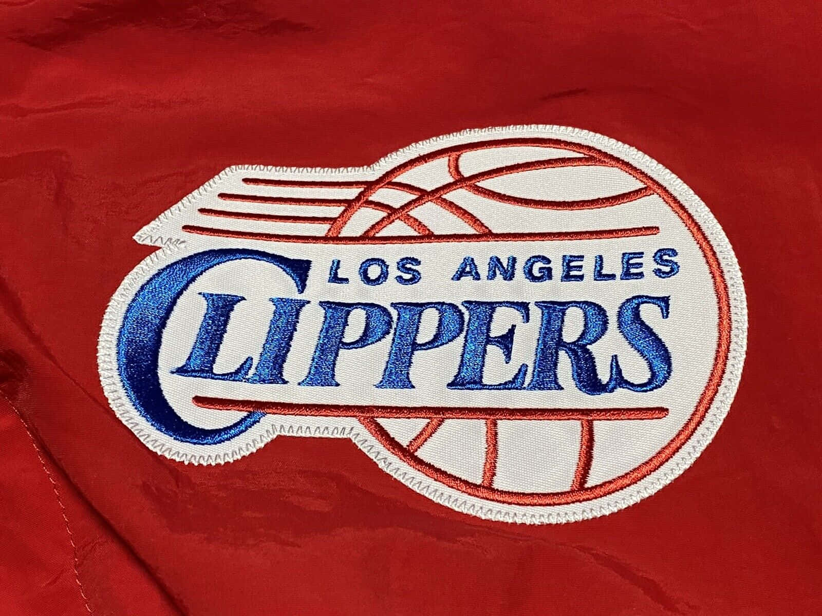 NBA 桌布 壁紙 — 紅色布料特寫，帶有刺繡的洛杉磯快艇隊標誌，包含藍色文字和白色籃球設計。