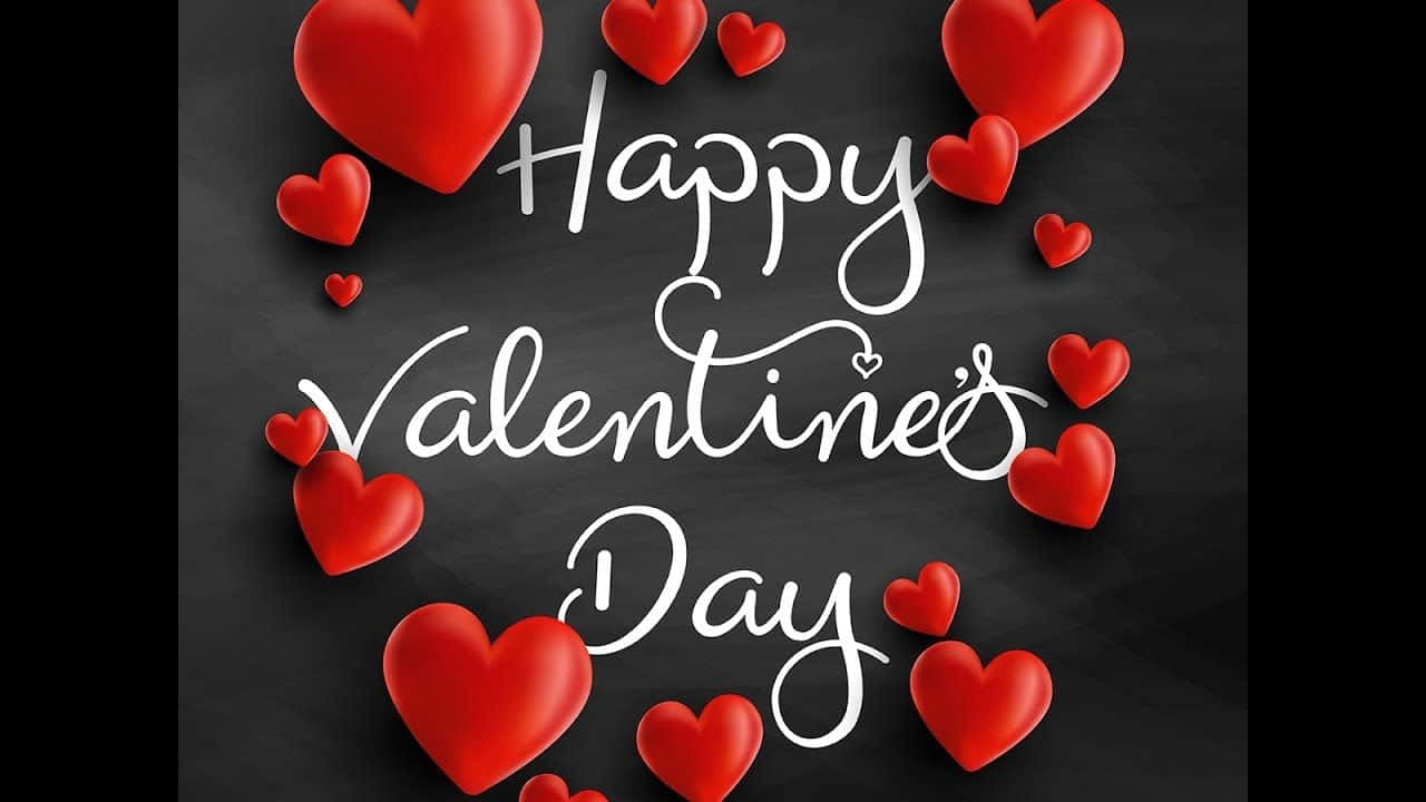Happy Valentines Day 桌布 壁紙 — 紅色心形在深色黑板背景上優雅的白色草書文字「Happy Valentine's Day」周圍漂浮。