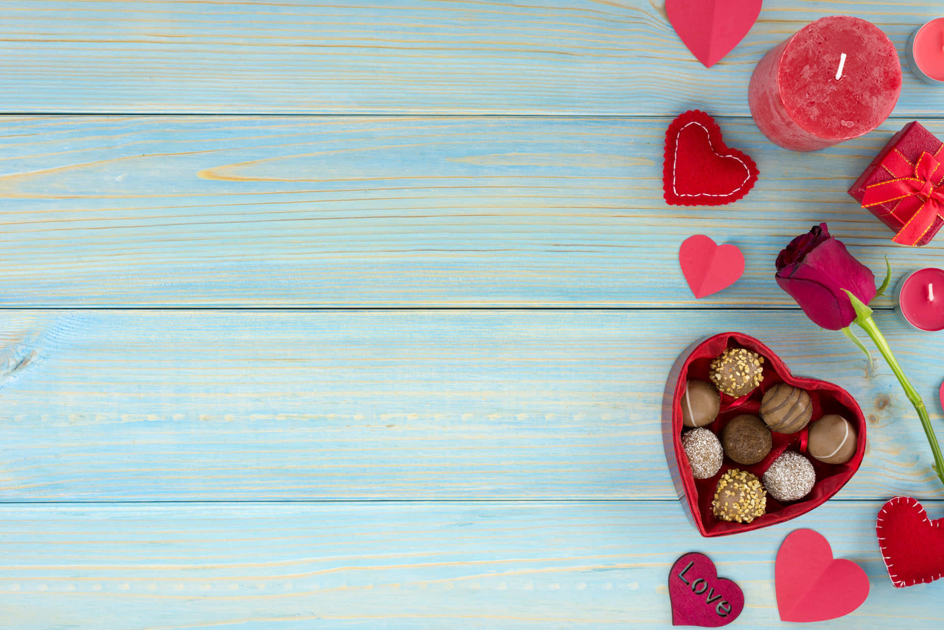 High Resolution Valentines Day 桌布 壁紙 — 紅色心形巧克力、玫瑰、蠟燭和紙心心點綴淺藍色木質表面，迎接情人節。