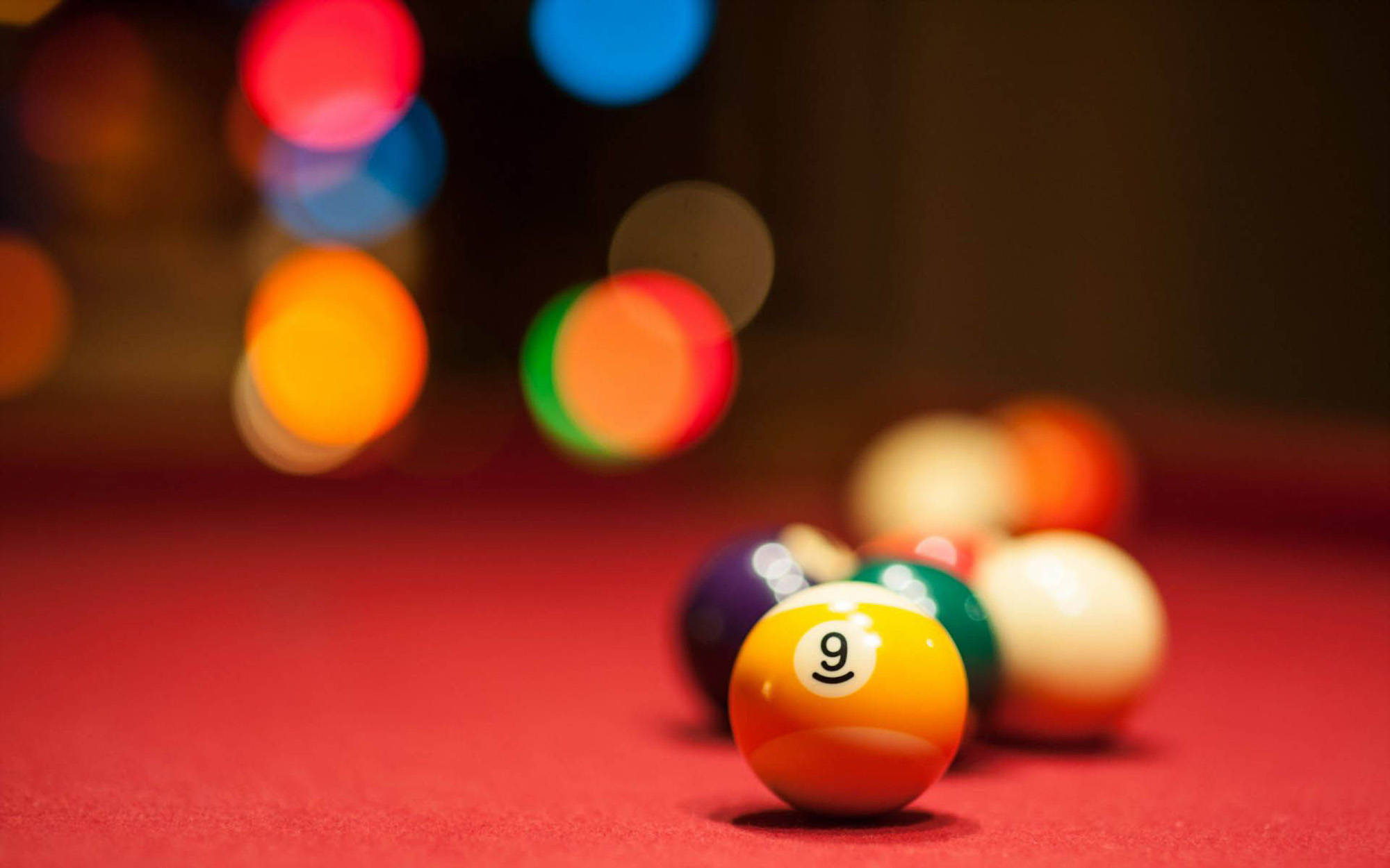 Snooker 桌布 壁紙 — 紅色撞球桌上黃色九號球的特寫，背景有彩色散景燈光。