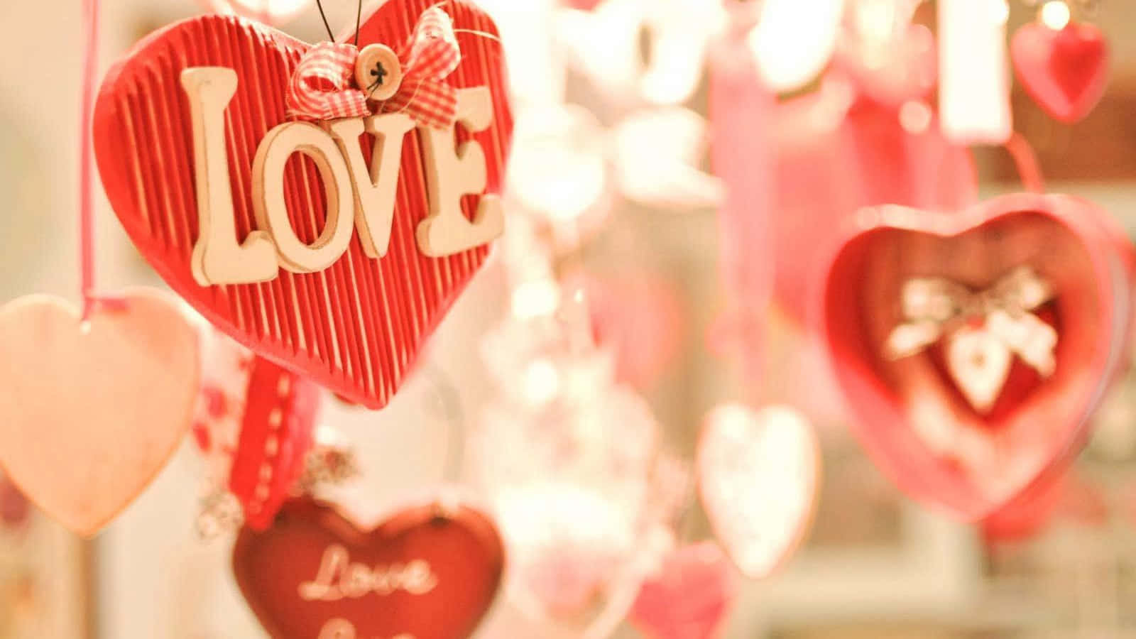 可愛情人節 桌布 壁紙 — 紅色木製心形掛飾，帶有「LOVE」字母，在溫暖浪漫的展示中柔和地亮起。