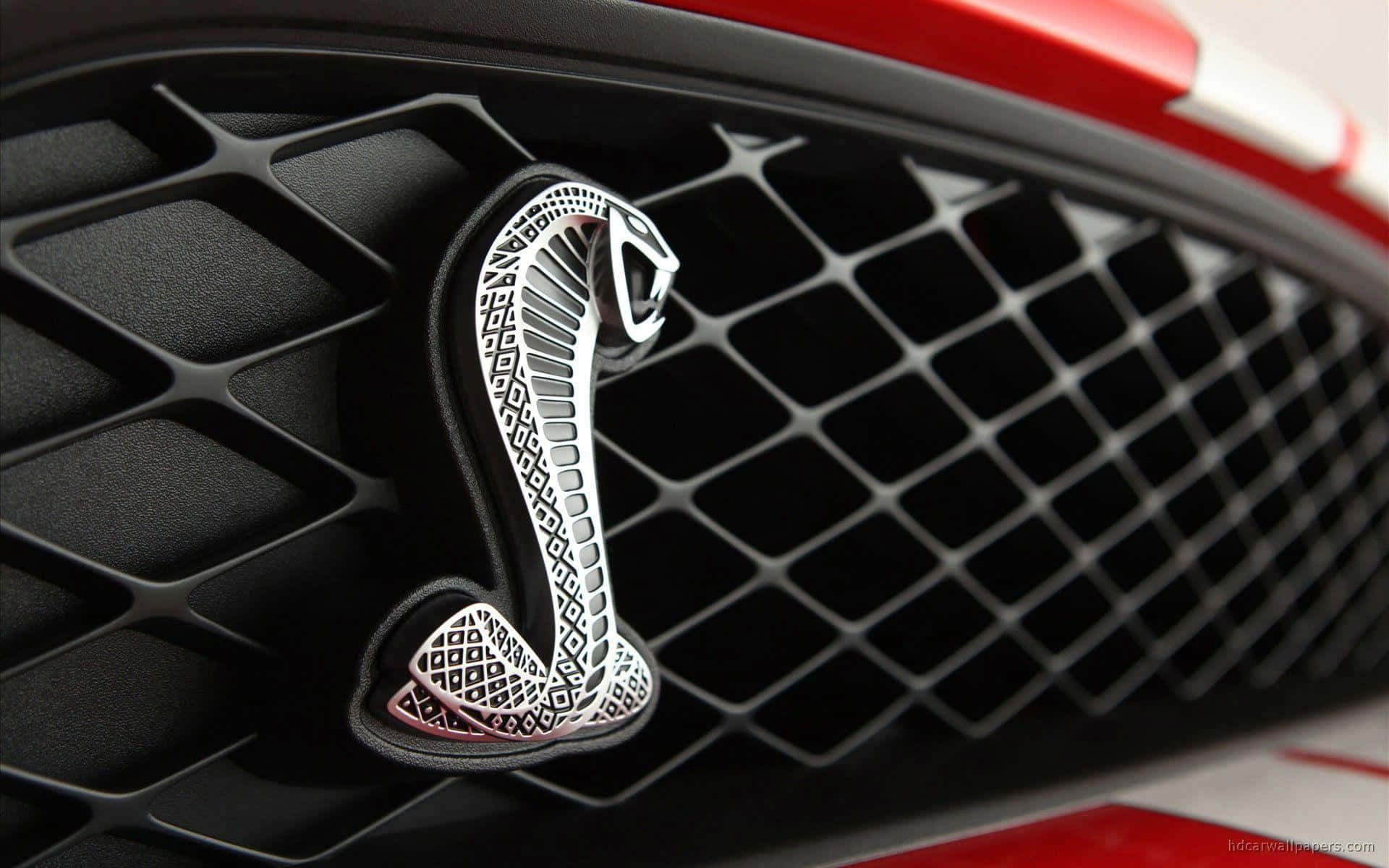 Car Logo 桌布 壁紙 — 紅色汽車黑色菱形圖案格柵上的鍍鉻眼鏡蛇標誌特寫。